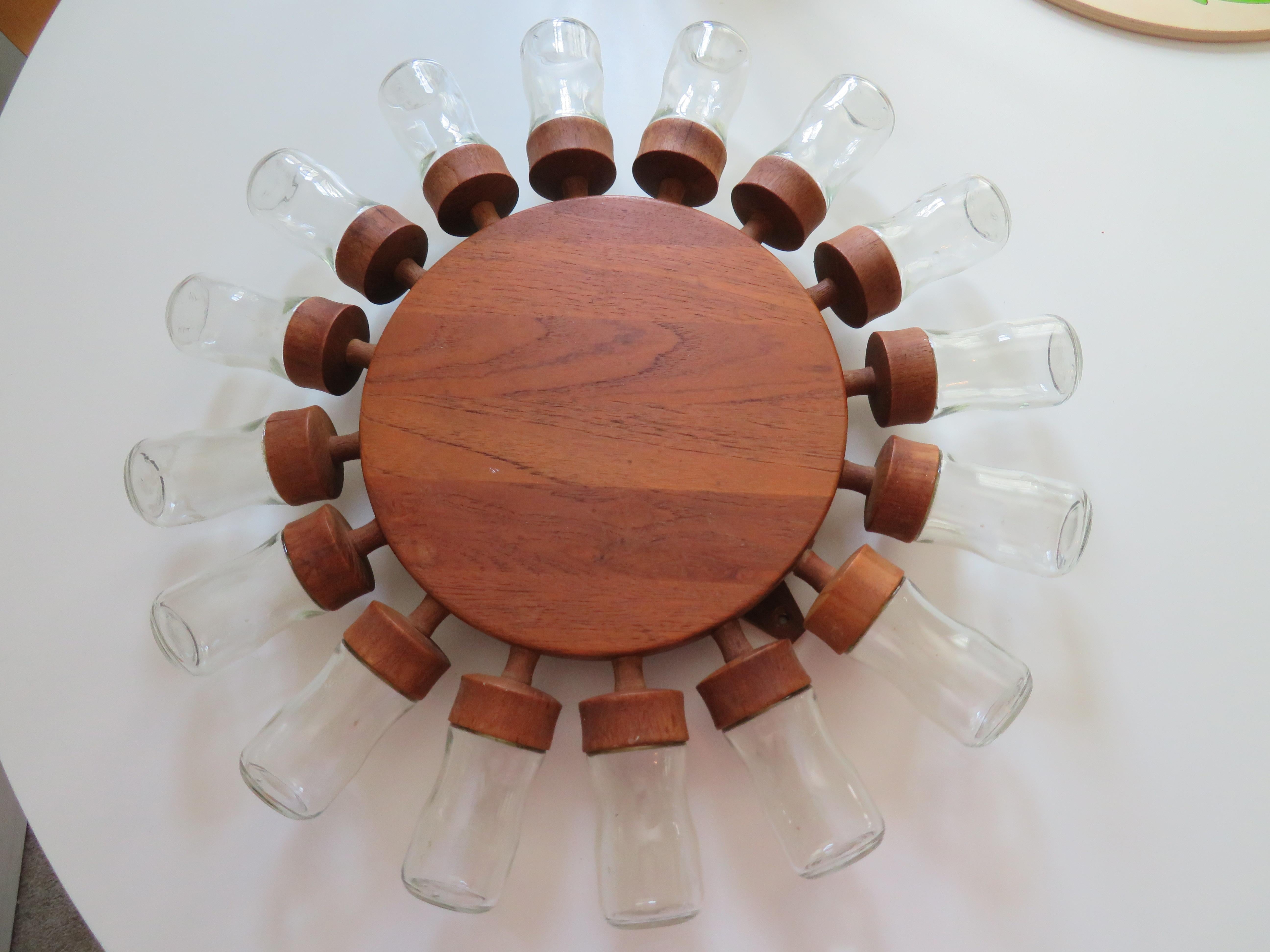 Esta rueda de especias danesa Digsmed para colgar en la pared, con marco giratorio de madera de teca, tiene 16 vasos extraíbles como recipientes para las especias. Original de los años sesenta.