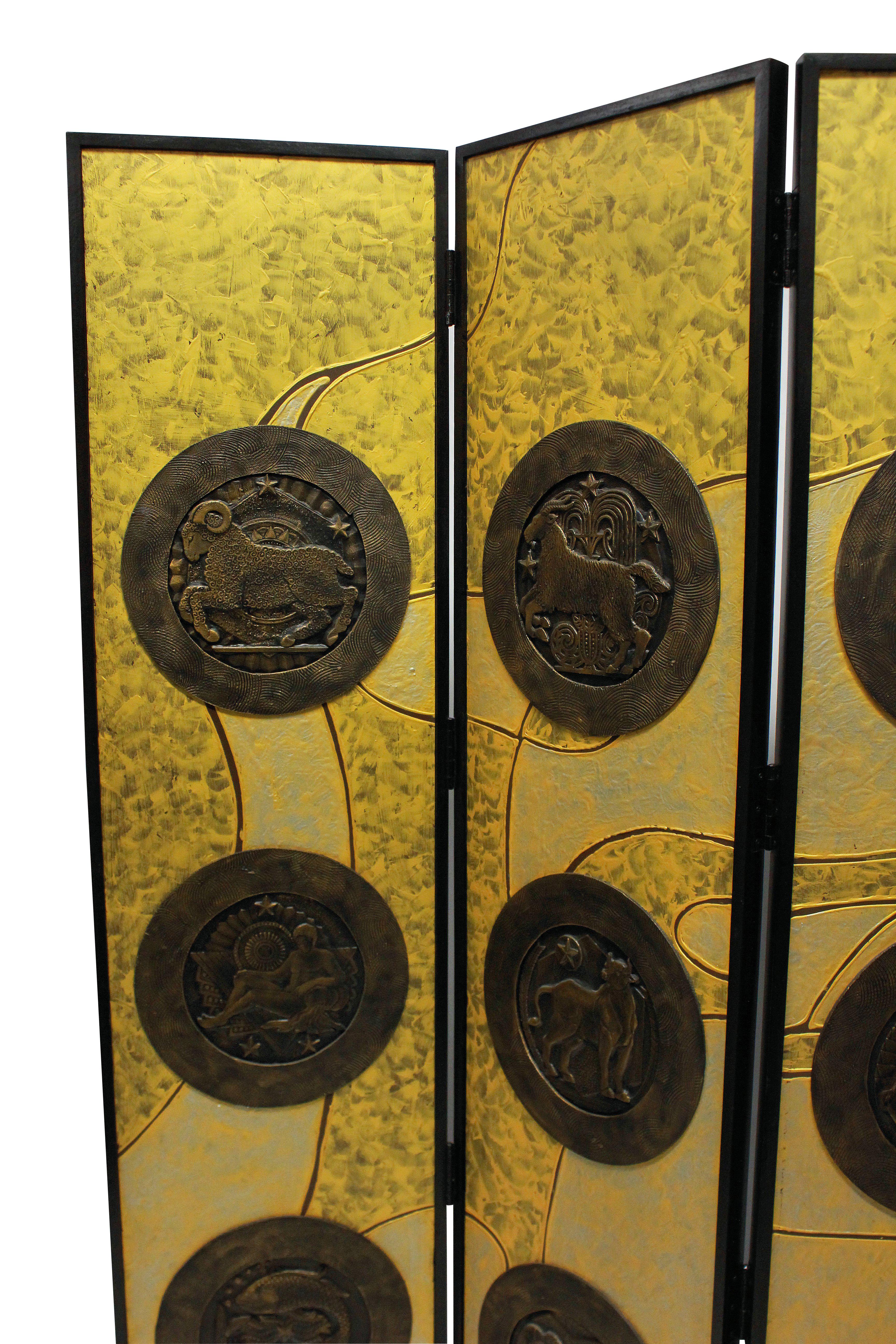 An Italian hand painted four-fold screen in the manner of Fornasetti, with a gold and yellow back ground supporting bronzed medallions of the zodiac symbols. Set in a hardwood ebonized frame, it is very heavy and sturdy.
