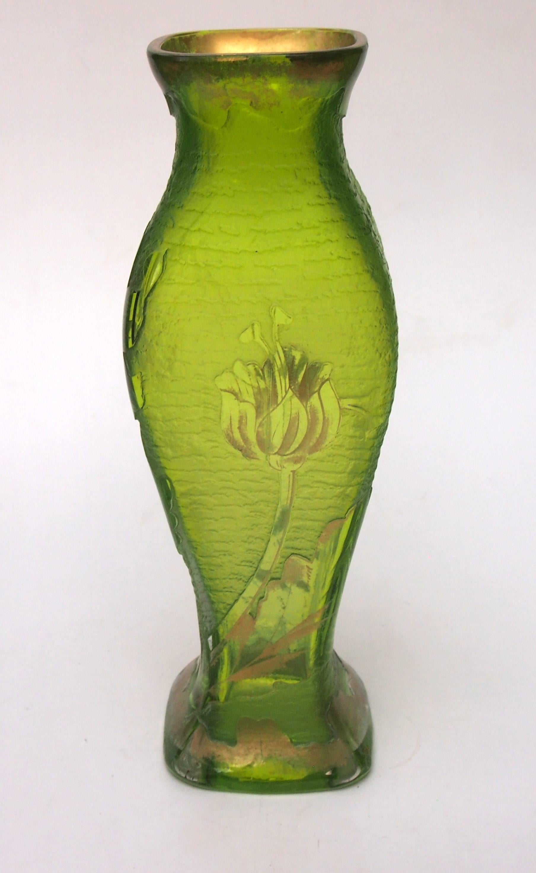 Deeply acid cut back and gilded cameo vase in yellow/green depicting fabulous lilies on all four sides. Unusually the acid cut back gives an impression of mottled bands laying behind the lilies. This slender elegant vase is by the great house of