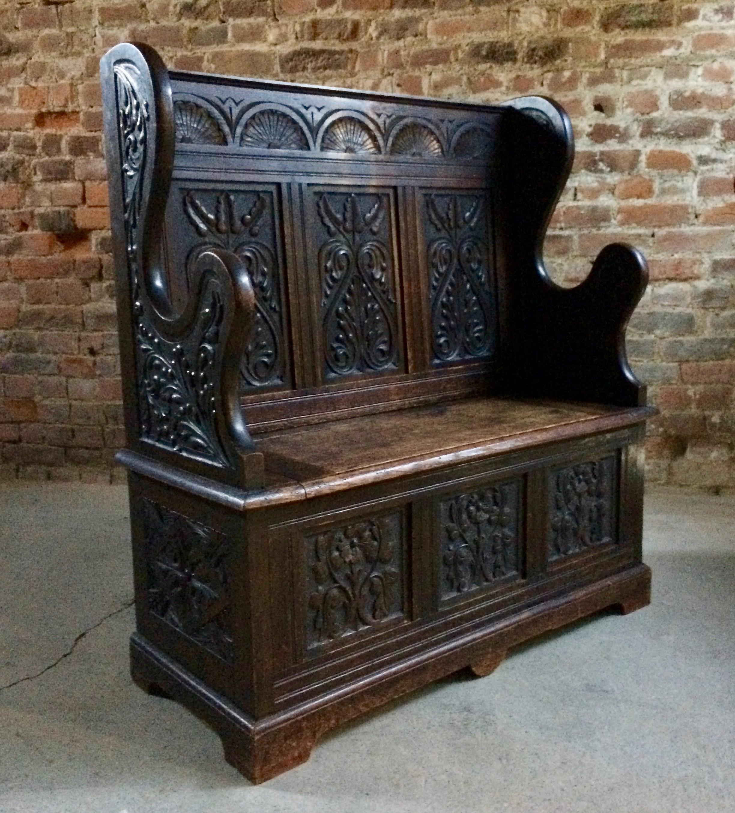 A beautiful 19th century profusely carved oak hall seat or box settle dating to circa 1890, this wonderful late Victorian settle also referred to as a 'Monks Bench' has a wonderful deep rich dark oak patina, the tall carved back with sunburst