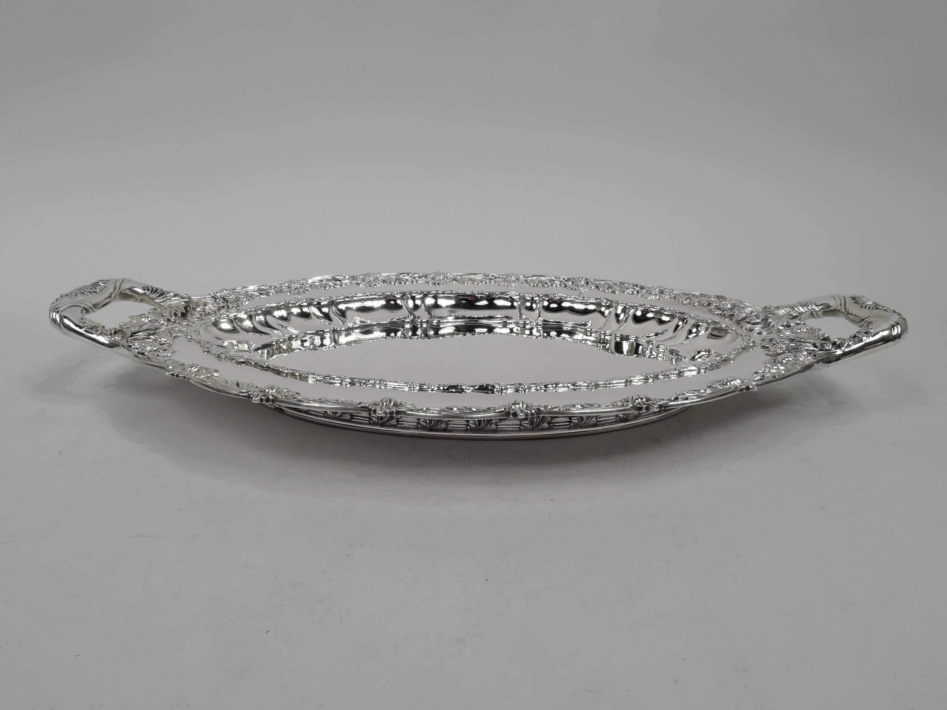 Chrysanthemum sterling silver serving dish. Made by Tiffany & Co. in New York. Shaped oval well, curved sides with lobing and applied leaf border. A profusion of blossoms bunched at ends and wrapped around bracket handles. Scalloped rim with