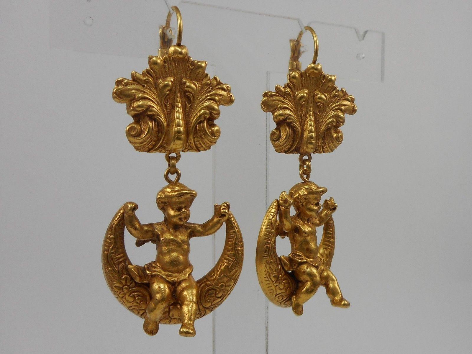 Wonderful pair of Cherub and Moon Dangle Earrings; Antiqued Gilt Brass; Cherubs are sitting on embossed Crescent Moons suspended from lever back earring fittings decorated with brass scrolls. Earrings measure approx. 2.50'' X 1.00''. Signed: ASKEW