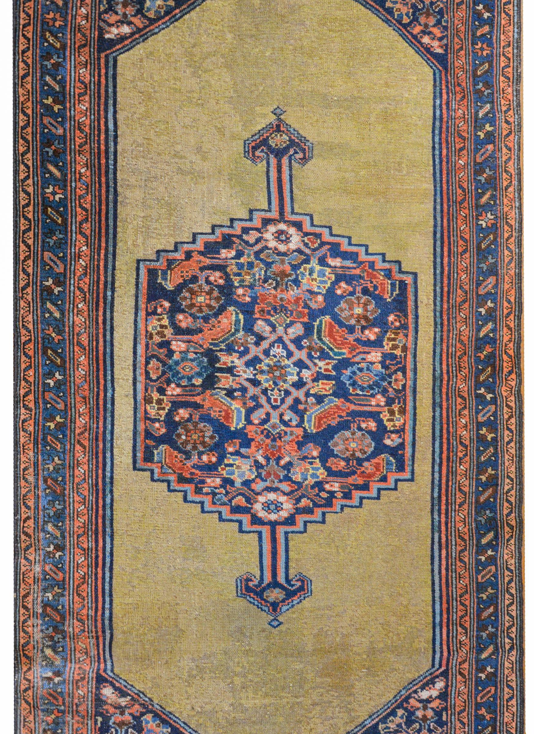 Un fabuleux anneau Serab persan du début du 20e siècle avec un grand médaillon central tissé avec un motif floral et de feuilles en treillis dans un fond indigo foncé sur un fond de couleur camel, le tout entouré de multiples petites bandes à motif
