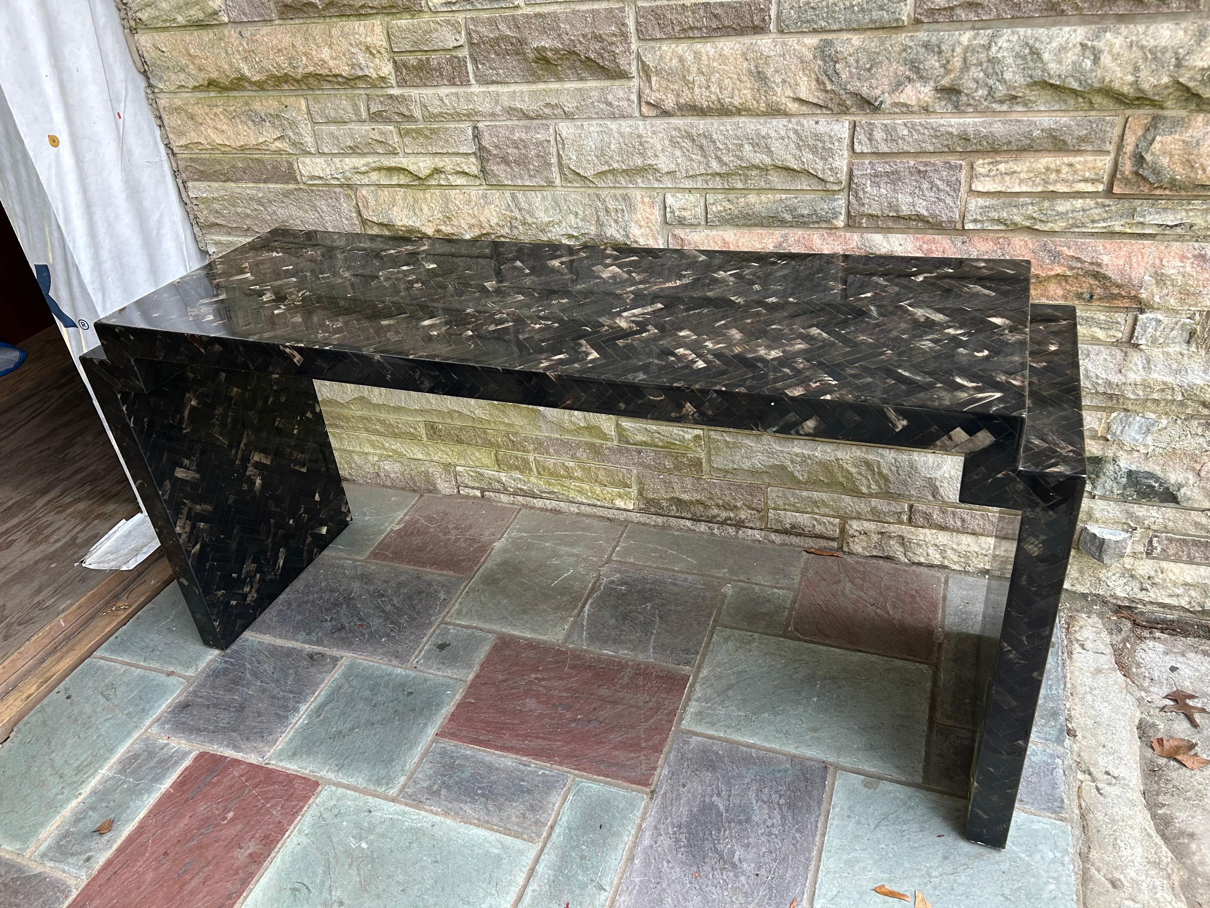 Striking and sophisticated Enrique Garcel  tessellated horn console table featuring geometric inlay of polished black and beige horn pieces arranged in a beautiful mosaic pattern. The bold, sculptural form with clean, angular lines gives it a sleek