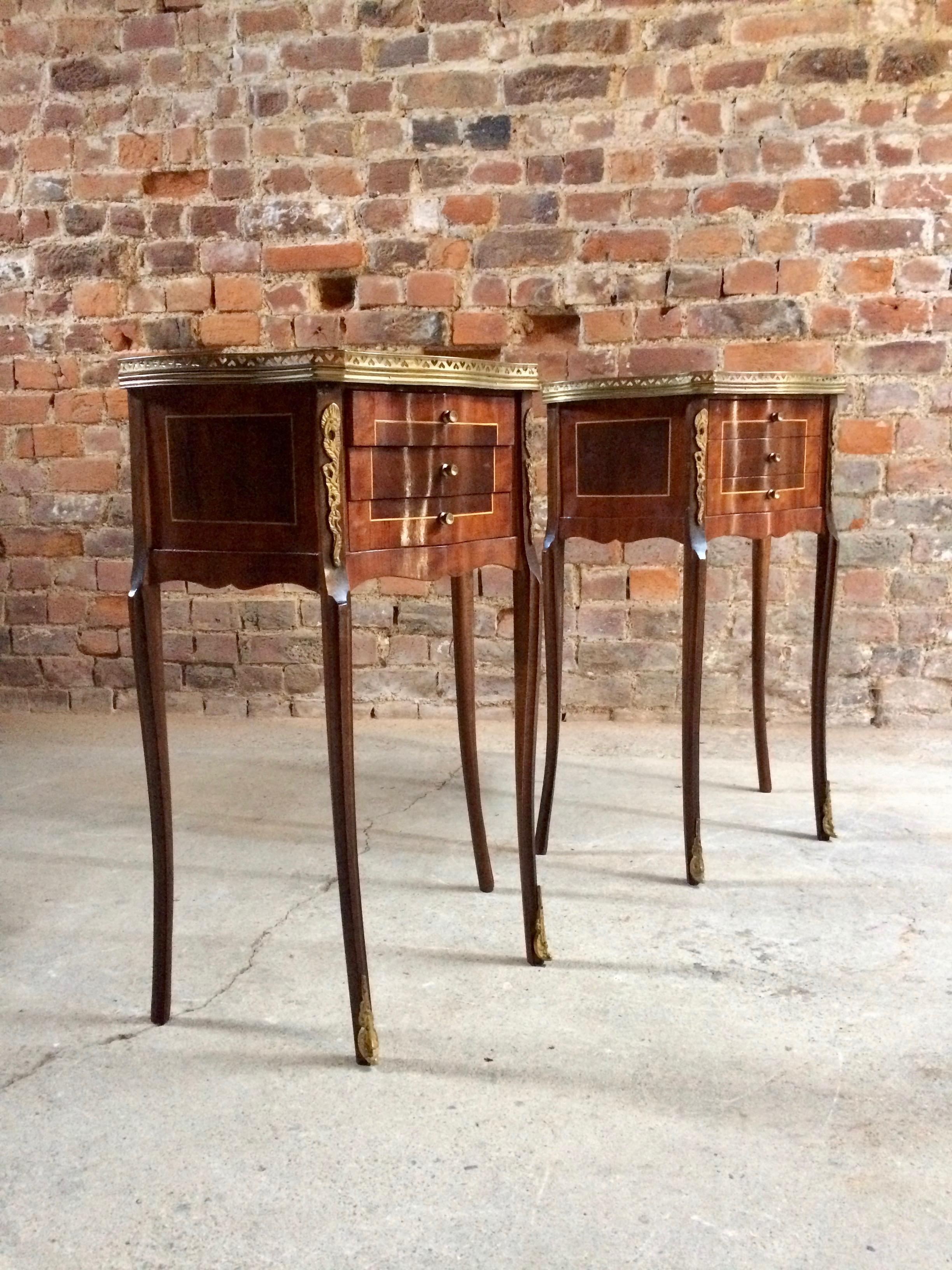 A wonderful pair of French rosewood and burr walnut bedside cabinets / nightstands or side tables dating from the mid-20th century, with applied brass galleried surrounds with inlaid tops over three short drawers with tall and elegant out swept legs