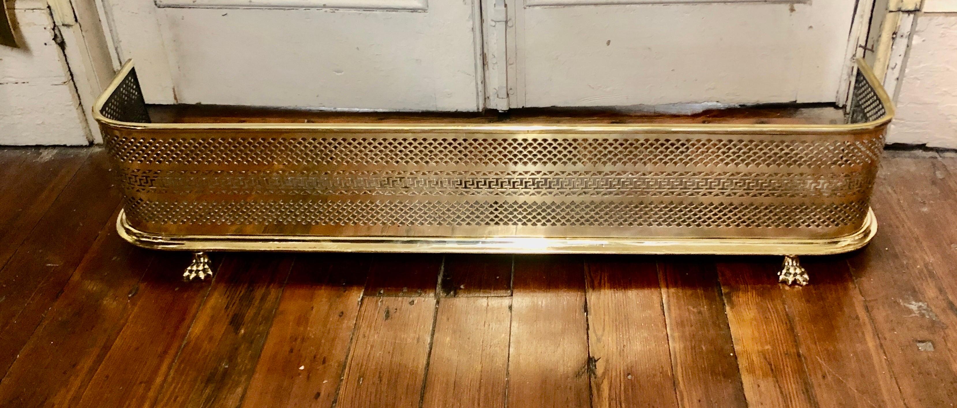 This is a wonderful and fine antique English Geo. IV pierced solid brass Fireplace Fender with handsome original cast brass lion's paw feet. It still retains its original steel pan and there is an illegible maker's mark (illustrated). This fender,