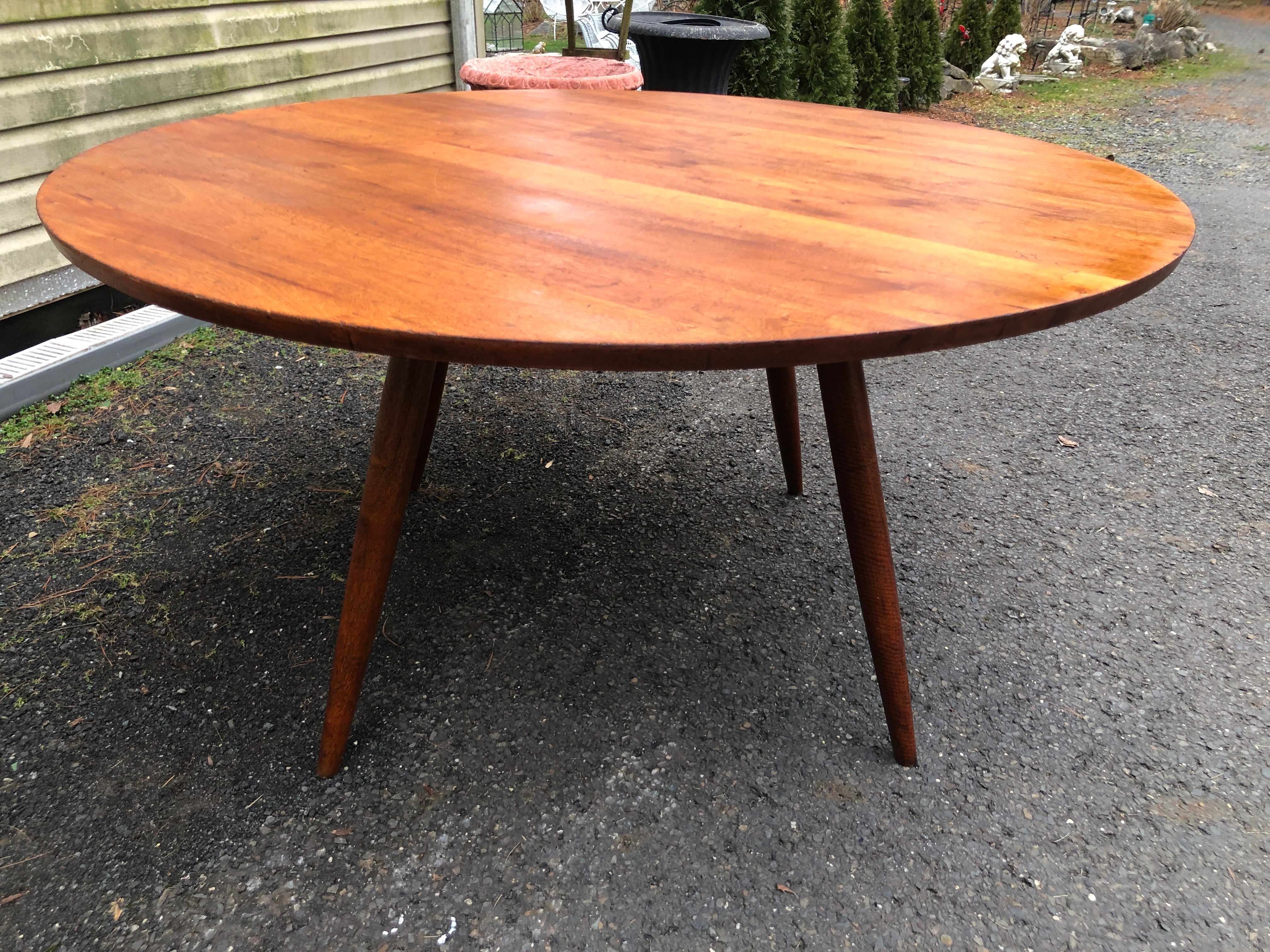 Amazing Black Walnut dining table from American midcentury craftsman George Nakashima. This wonderful table features four splayed tapered dowel legs which support a large round table top.  The table top does show some light wear with minor scratches