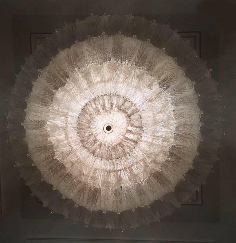 Réalisé en pur verre de Murano, chaque lustre est composé d'un nombre incroyable de feuilles. La structure est plaquée or. 18 lumières diffusent une lumière magique. Mesures : diamètre 156 cm, hauteur 58 cm et chaîne. Sont également disponibles