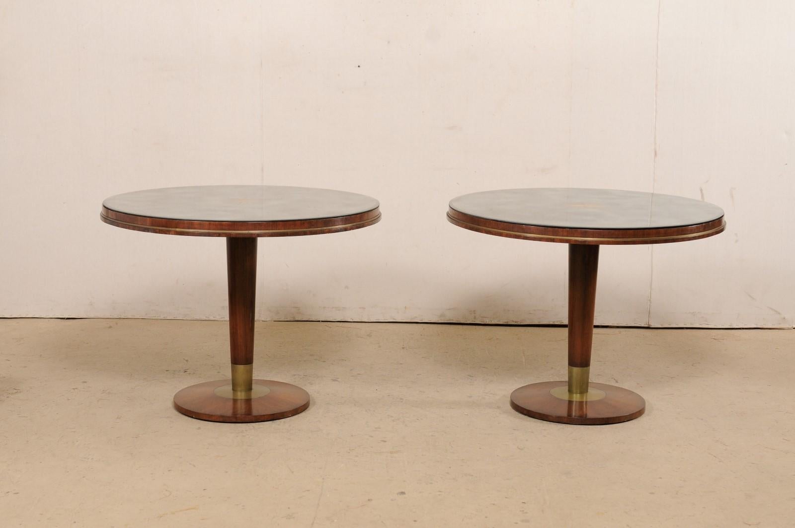 A gorgeous pair of custom eglomisé mirror top tables on mid 20th century Italian bases. These mid-century tables have each been fashioned with an artisan-made, 40 inch round-shaped antiqued mirror top, with a verre églomisé sunburst at their center.