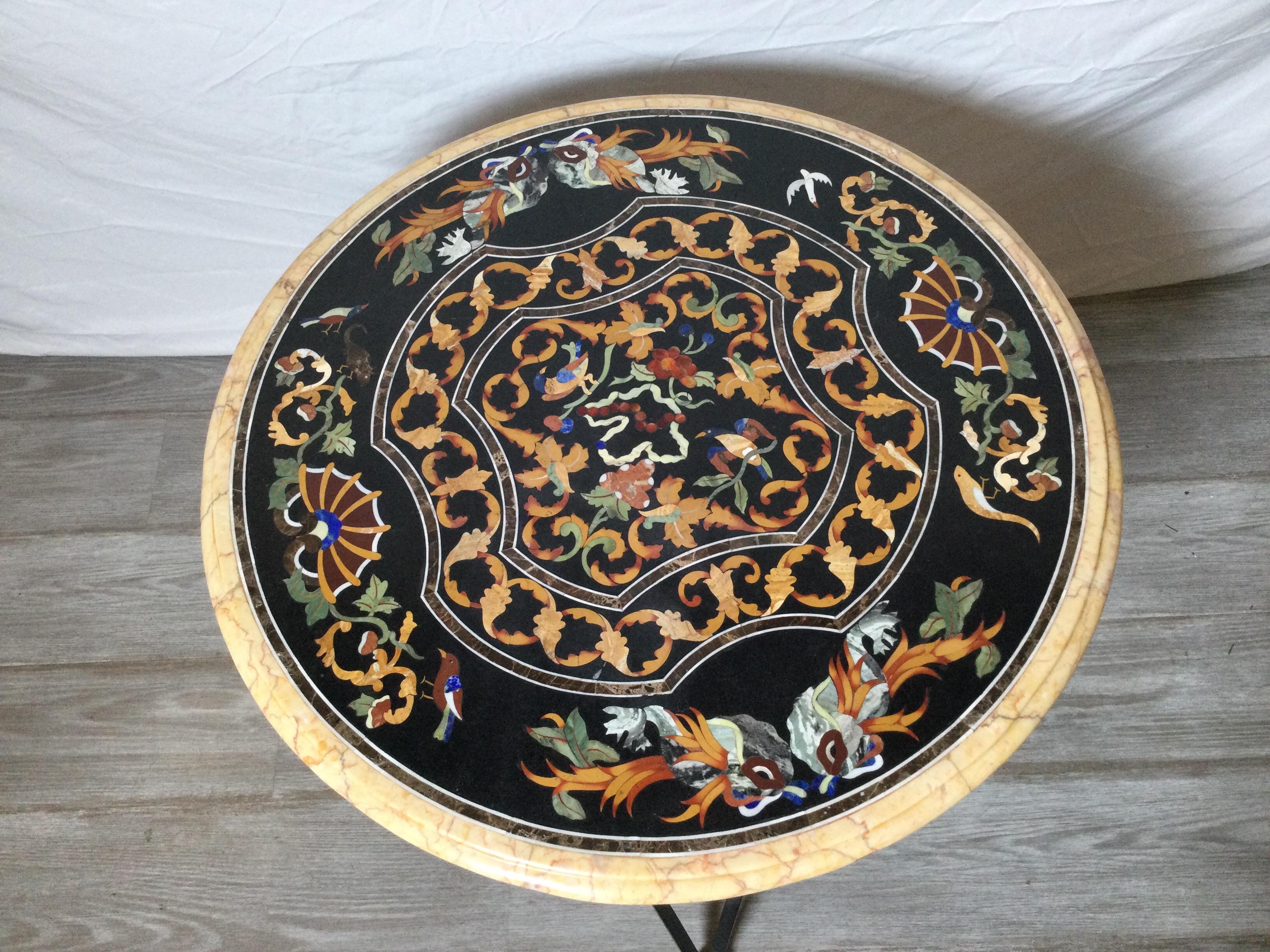 Vibrant pietra dura table with blackened iron base. The beautifully inlaid top with lapis, malachite and other colorful stones on a slate background. The bleck iron base with brass accented rosettes.