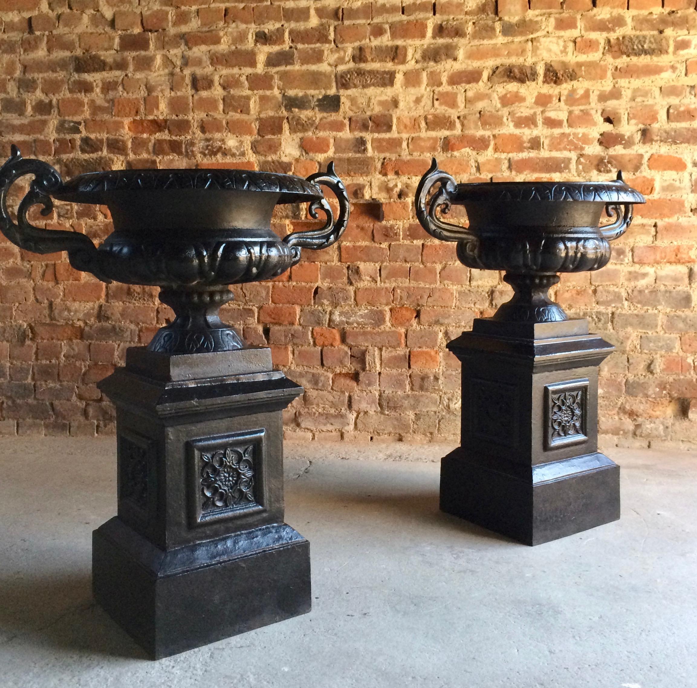 Fabulous pair of large antique cast iron garden urns dating to late 19th-early 20th century, the urns with outstretched handles, sitting on raised square pedestal, will enhance any garden or front of house entrance, please note these items come in
