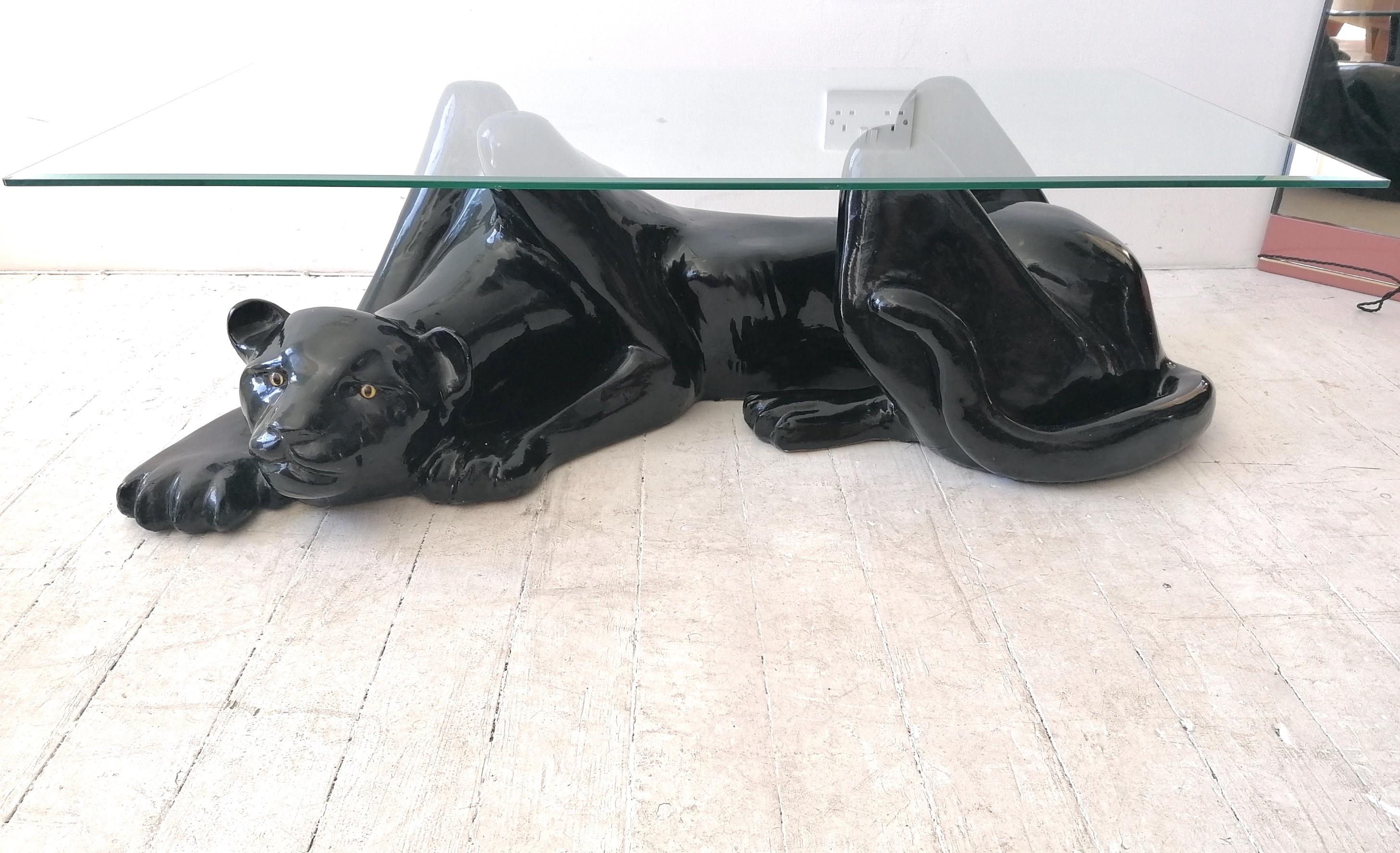 Large Art Deco Revival black panther coffee table with bevelled glass top. Sourced in Palm Springs, USA. Dates from the late 1970s/ mid 80s. The heavy fibreglass (feels like ceramic) panther crouches under a glass top. He has glass eyes.
Very hard