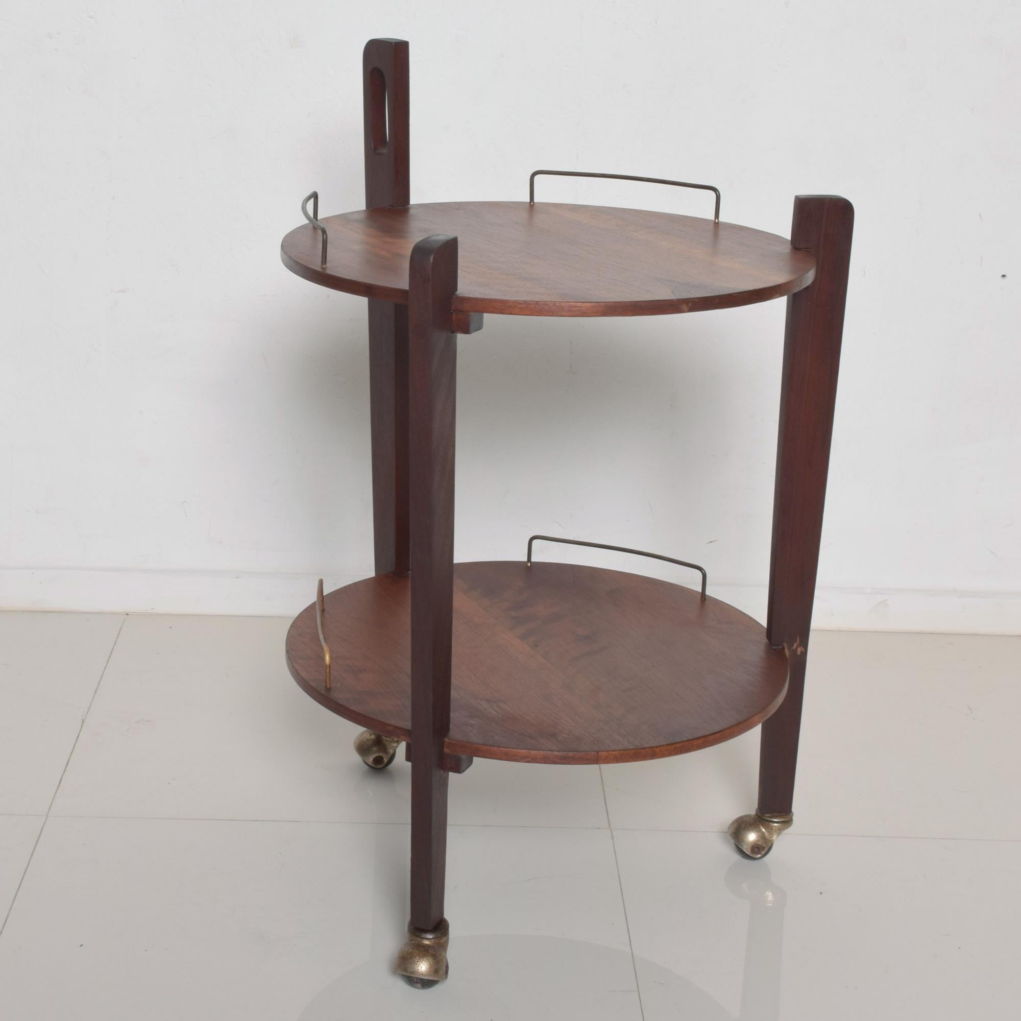 Fabulous Mexican Modernist sexy service cart trolley bar side table in wood with brass accents on casters.
In the manner of Eugenio Escudero. No label present.

Striking 2-tiered modern design

Dimensions: 32