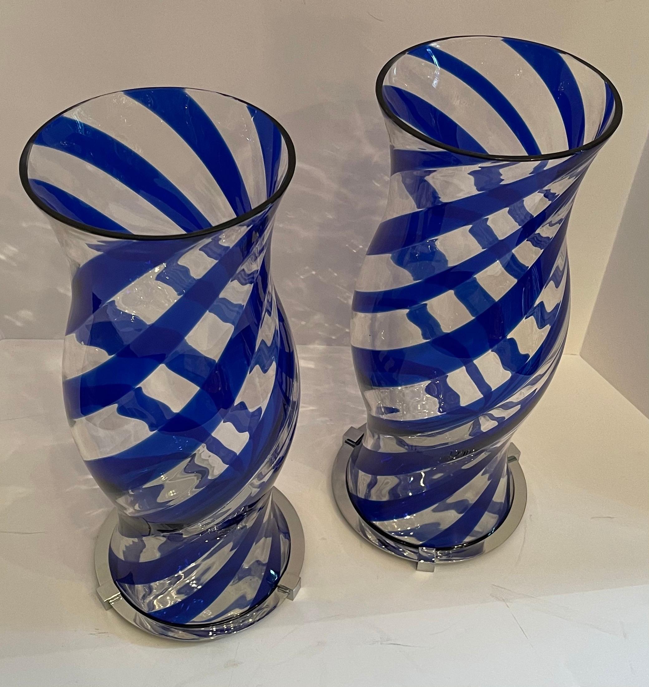 A fabulous modern pair of Lorin Marsh hand blown Murano blue swirl art glass hurricane shades each sitting on polished nickel bases.