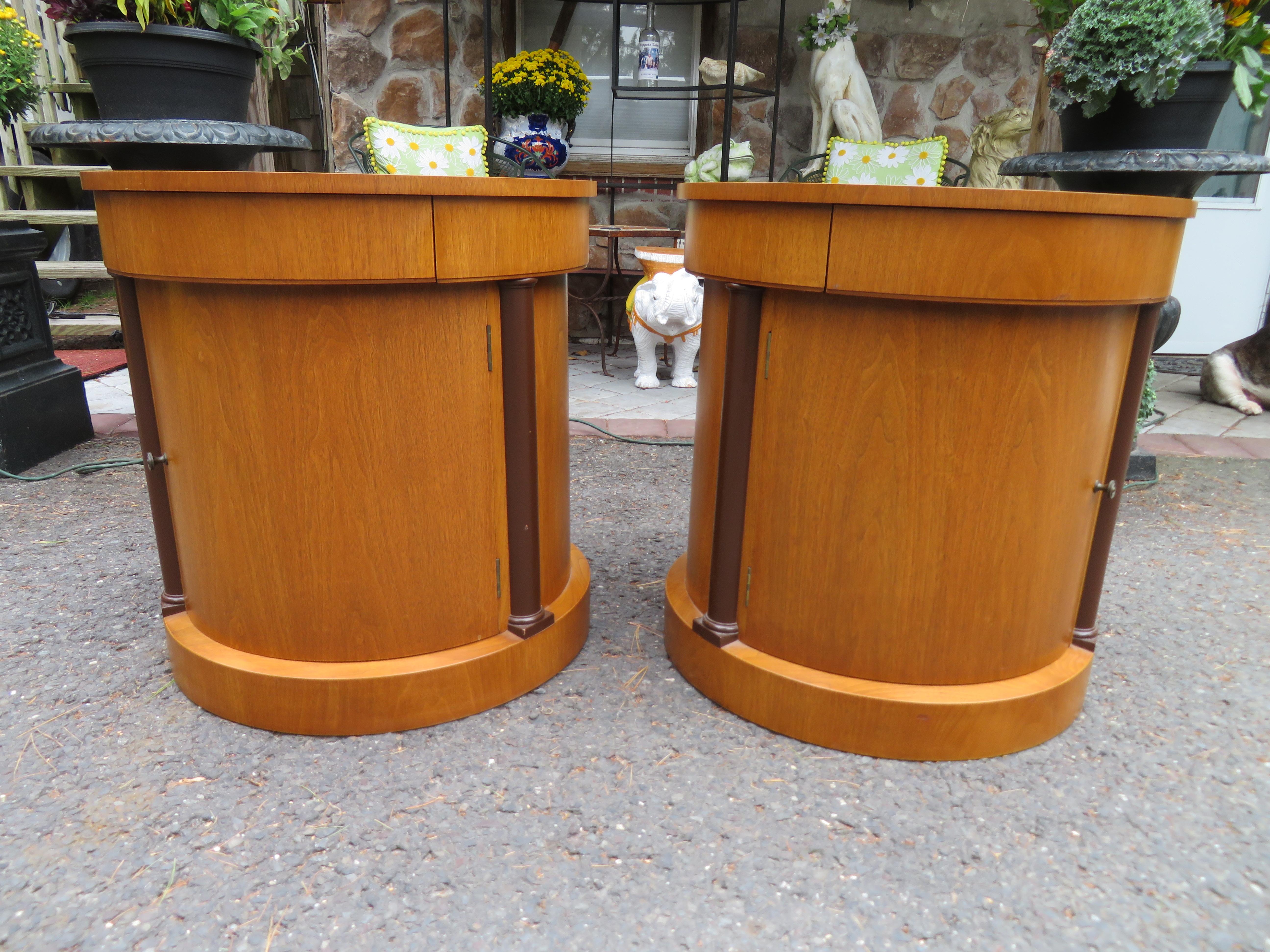Fabulous pair of Baker Neoclassical drum end tables. Feature circular top and base, one hidden drawer, and a single door opening to a storage space with one adjustable shelf. We love these used in the living room as end tables or in the bedroom as