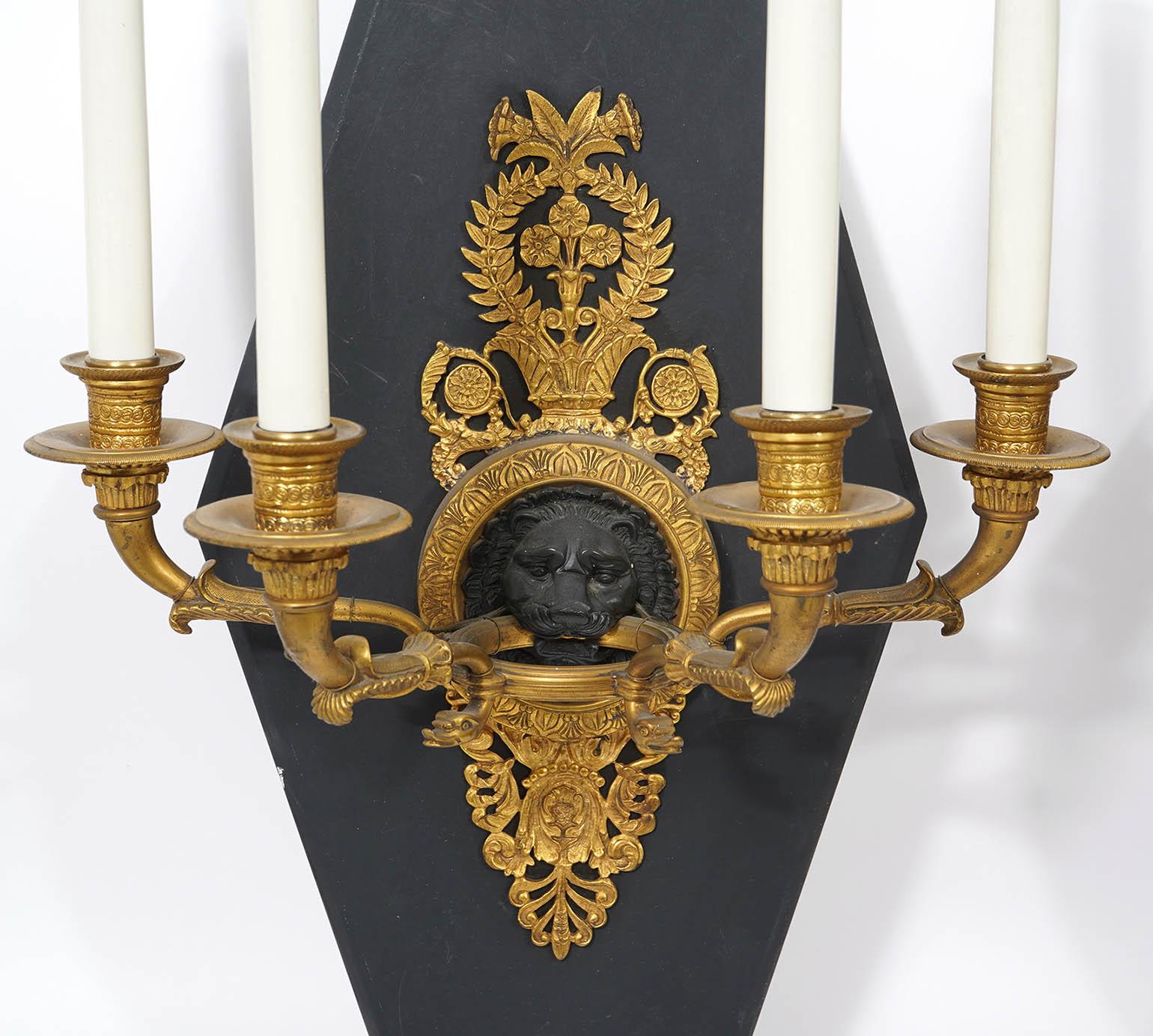 Fabulous pair of French gilt bronze empire sconces. Lion with open mouth holding up the candelabra. 19th Century, circa 1820's. Mounted later on wood backs to help mount on wall (Can be removed). Well detailed bronze work with Lion's mouth holding