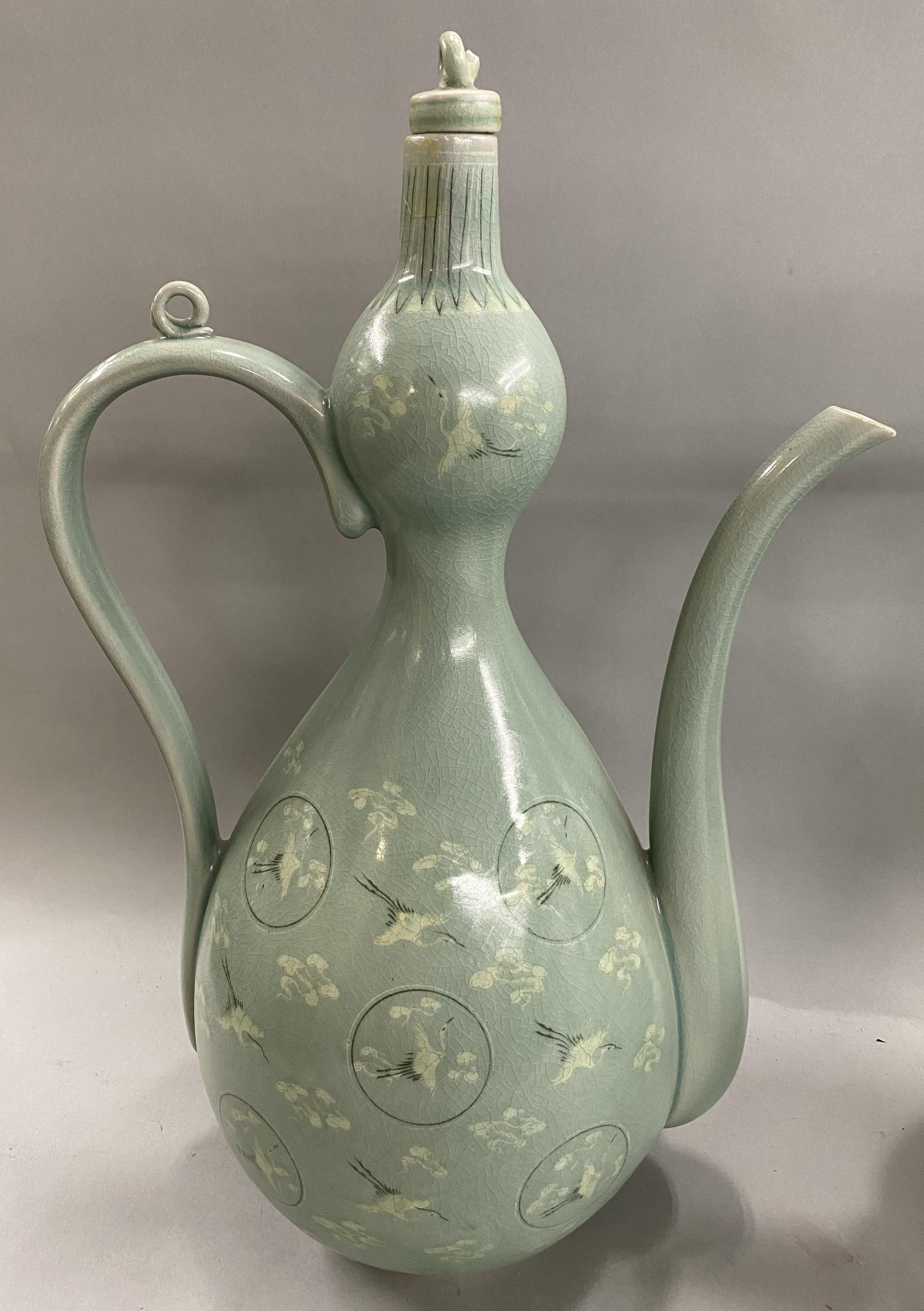 A fabulous fine pair of Korean green stork decorated celadon ewers with finial stoppers and delicate pour spouts, probably dating to the early to mid 20th century, in very good condition, with minor restorations and glaze imperfections, as well as