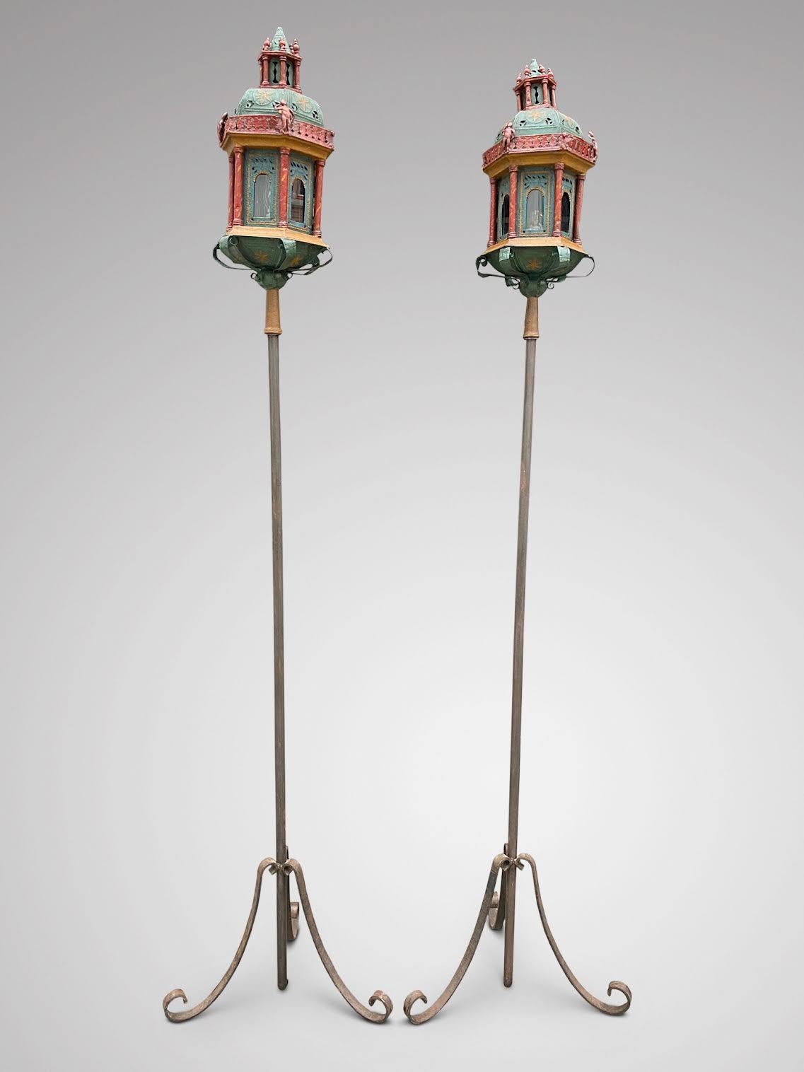 A fabulous pair of 19th century hand painted and hand crafted Venetian gondola tôle lantern torcheres, each with hexagonal lantern adorned with decorations, figures and scrolling foliage, on wrought iron stand scrolling tripod base. Newly