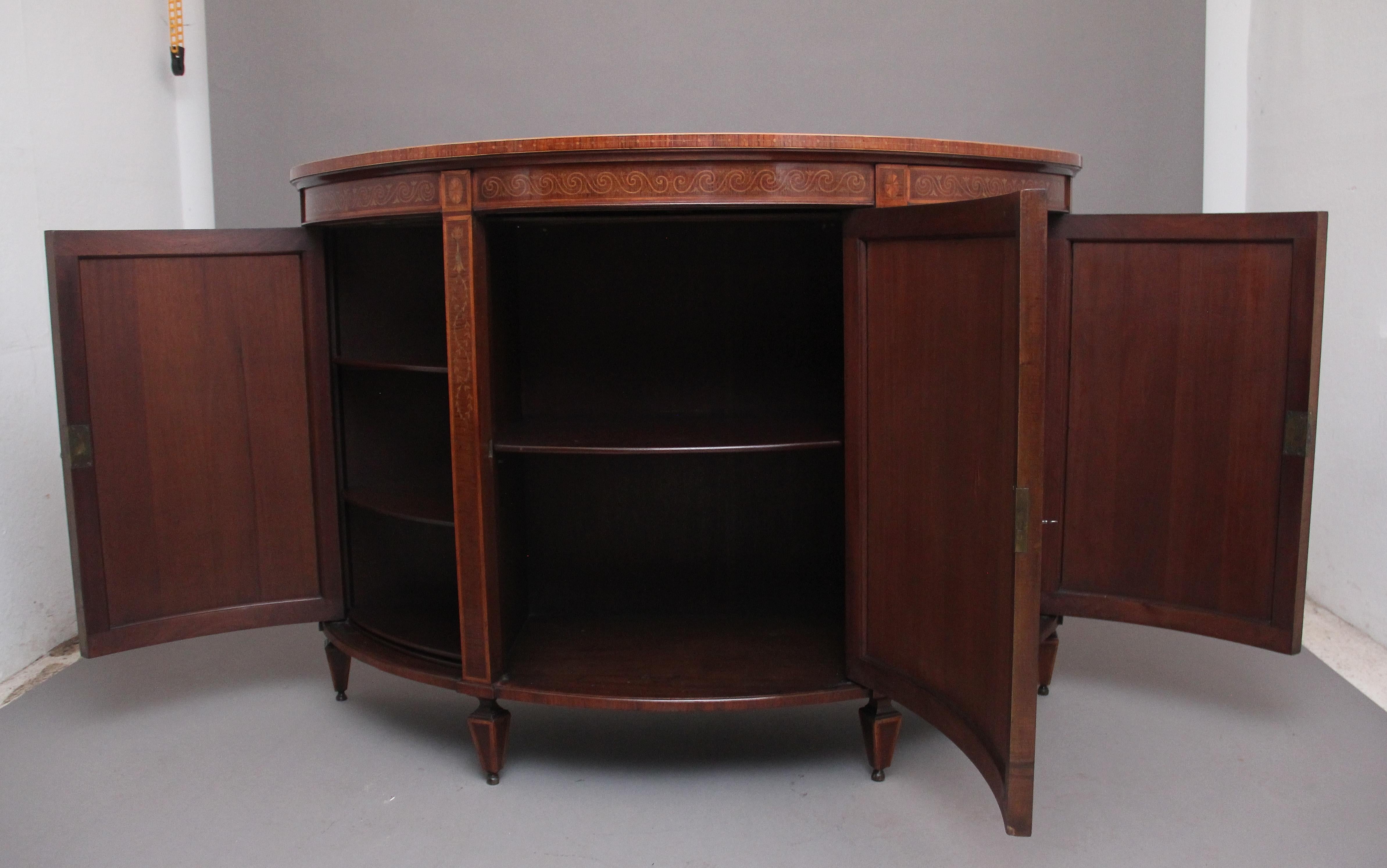 A fabulous quality 19th Century mahogany and inlaid demi-lune side cabinet in the Sheraton style, the shaped and inlaid top cooperating a decorative urn and floral inlay, the frieze below decorated with a swirl inlay pattern, the cabinet having a