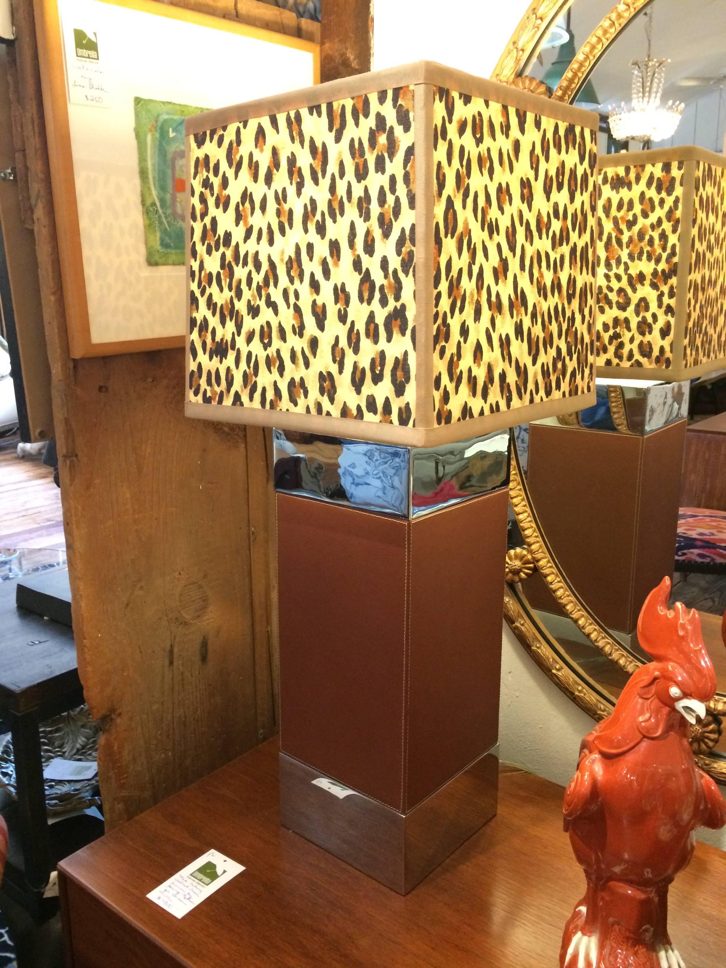 A very rich looking designer pair of table lamps having square leather clad bases with chrome detailing and visible handsome tan stitching, topped off with Mary McCarty handmade animal fabric shades.
Column of lamp is 7 inches square.
