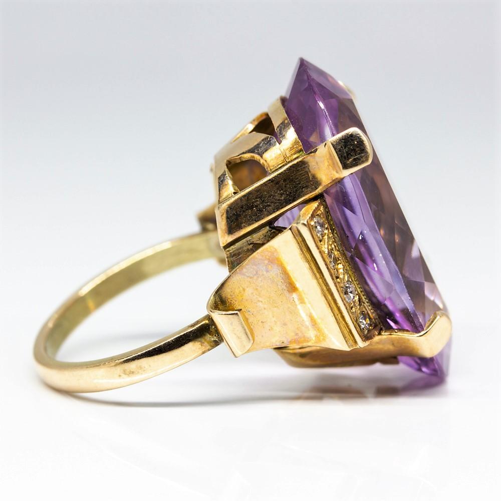 This fascinating ring was handcrafted in 1940’s and displays a fabulous Retro style with a central flawless oval cut amethyst that weighs 40ctw. 
The 18k gold band is encrusted on both sides with 8 single cut diamonds of H-SI1 quality that weigh