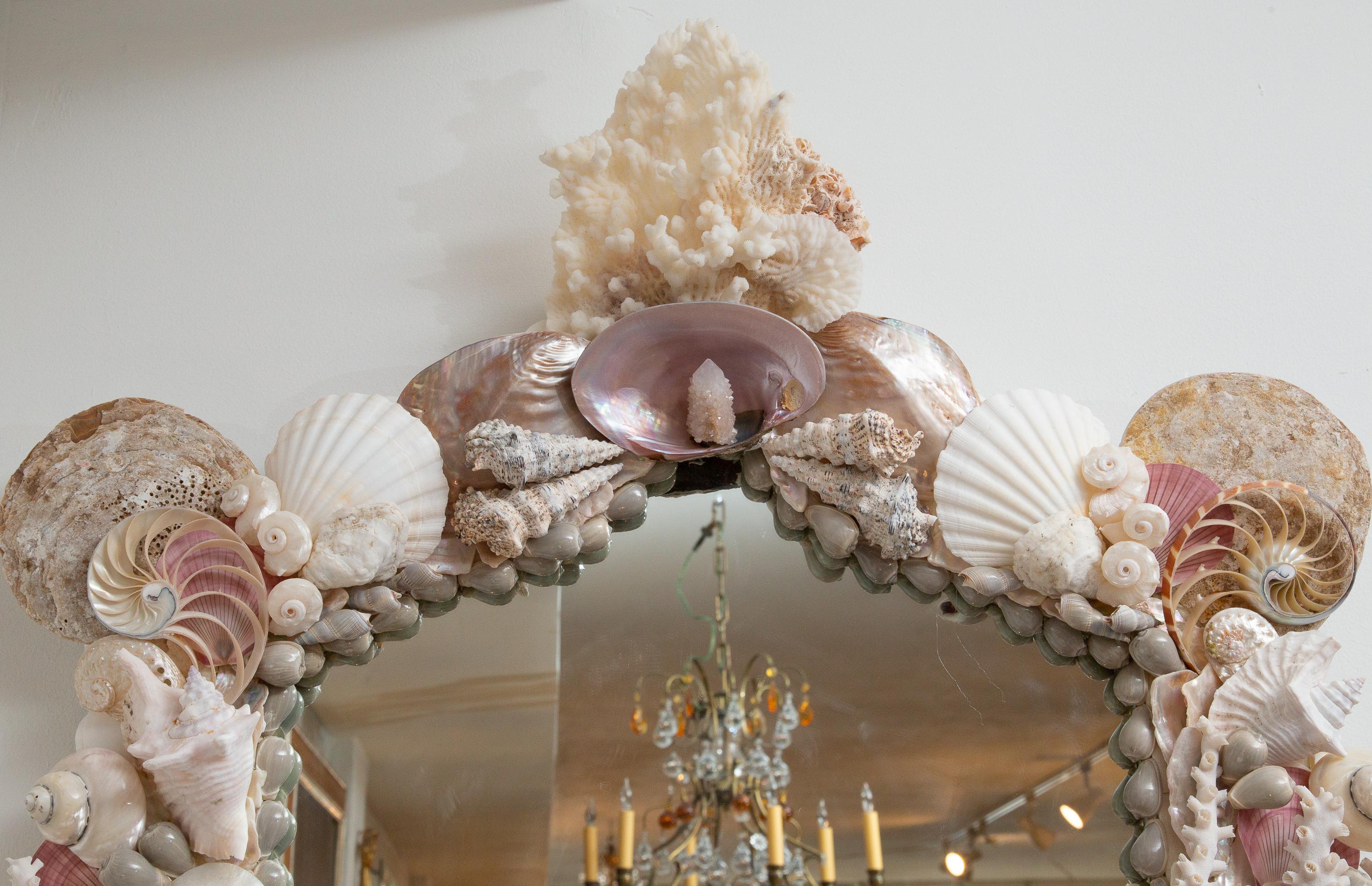 This is a unique mirror with an arching cornice. This custom mirror is composed of a variety of exquisite shells.