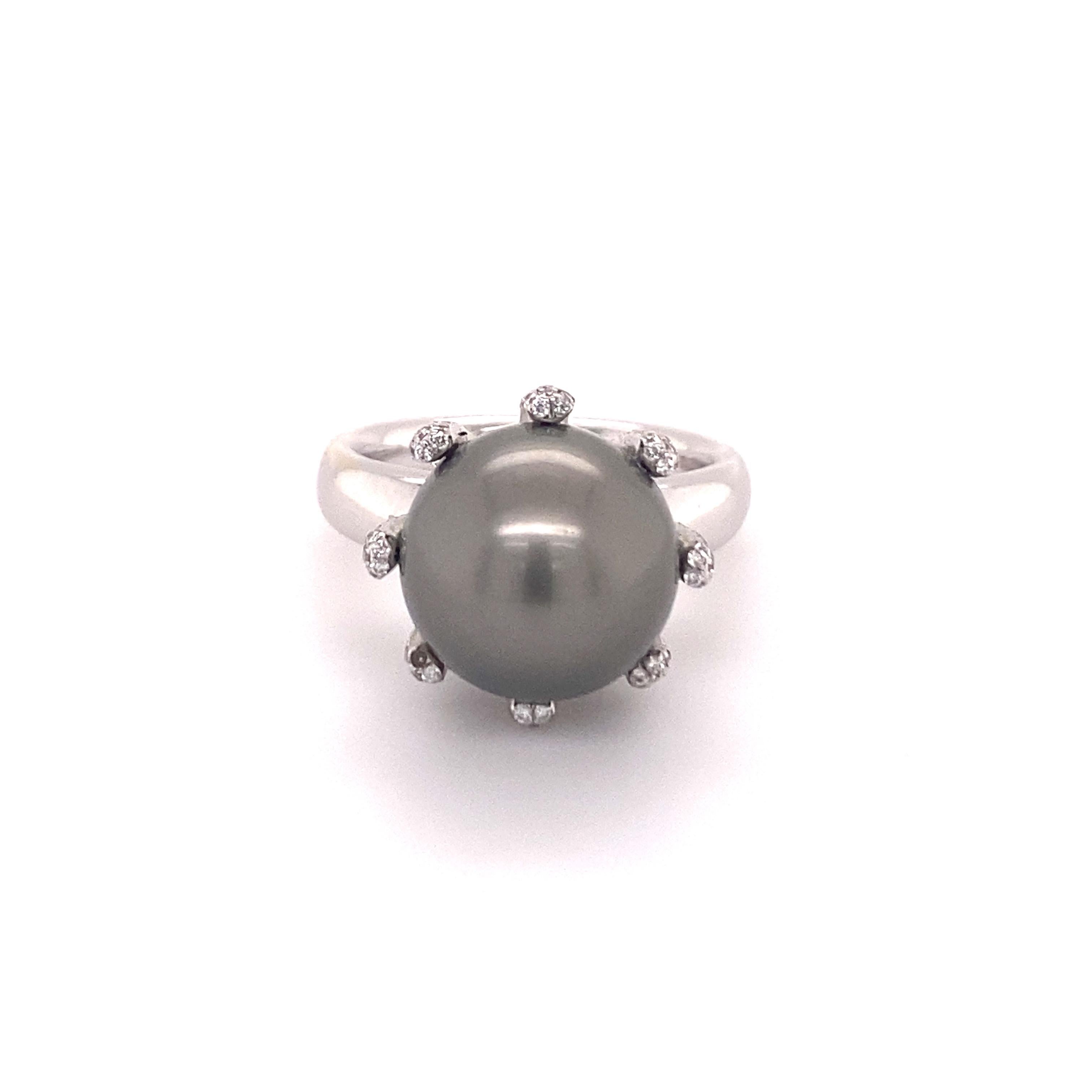 Gorgeous ring manufactured in 18 karat white gold centering one Tahitian Cultured Pearl of 12.0 mm in diameter. The pearl is of perfectly round shape with a medium dark-gray bodycolor. The surface shows minor blemishes combined with a very good