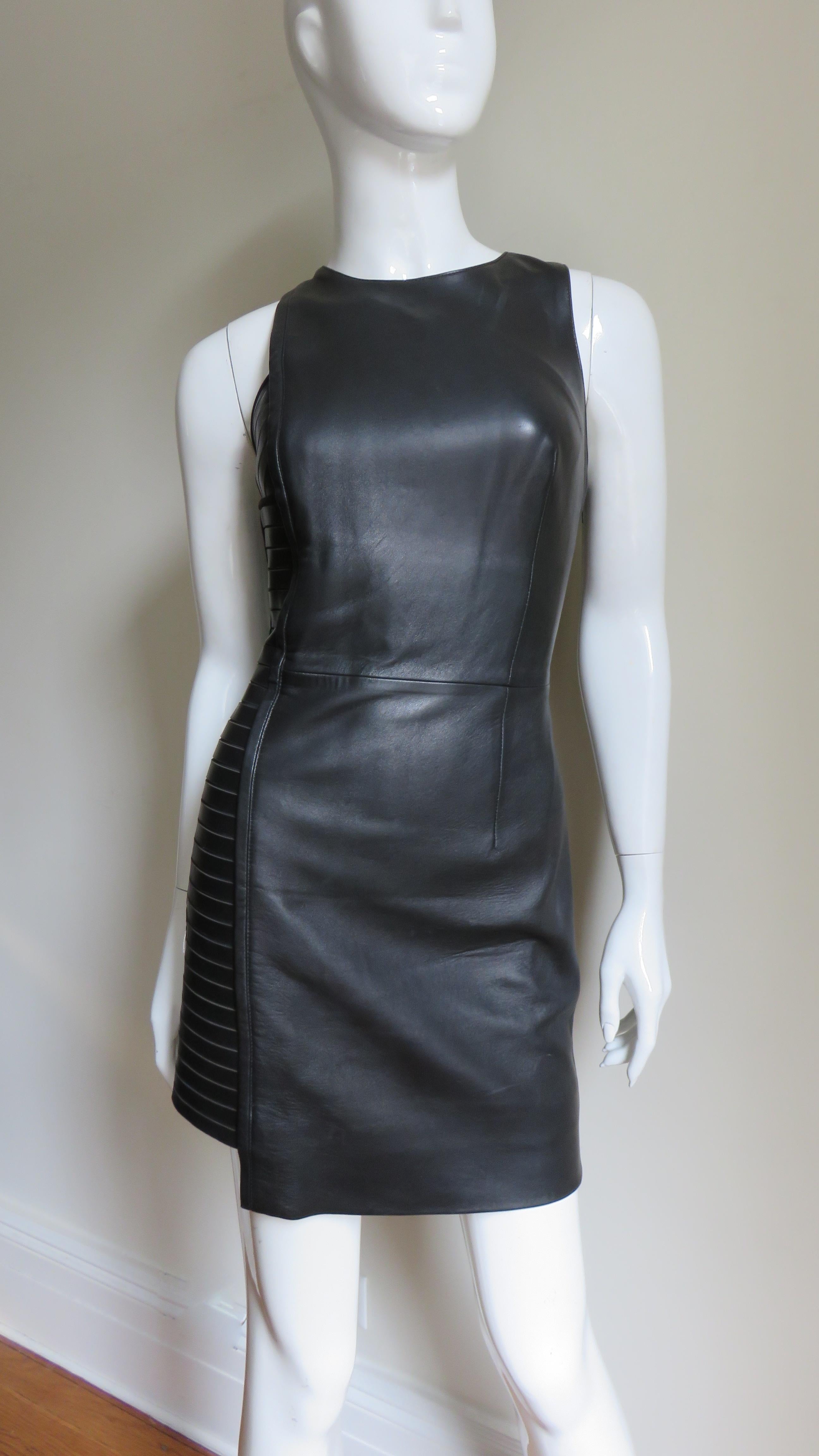 A great black leather dress from Versace.  It is sleeveless, fitted with a shorter length insert at one side consisting of horizontal strips of leather with piped suede at the seams.  It is fully lined in black, has an invisible side zipper and