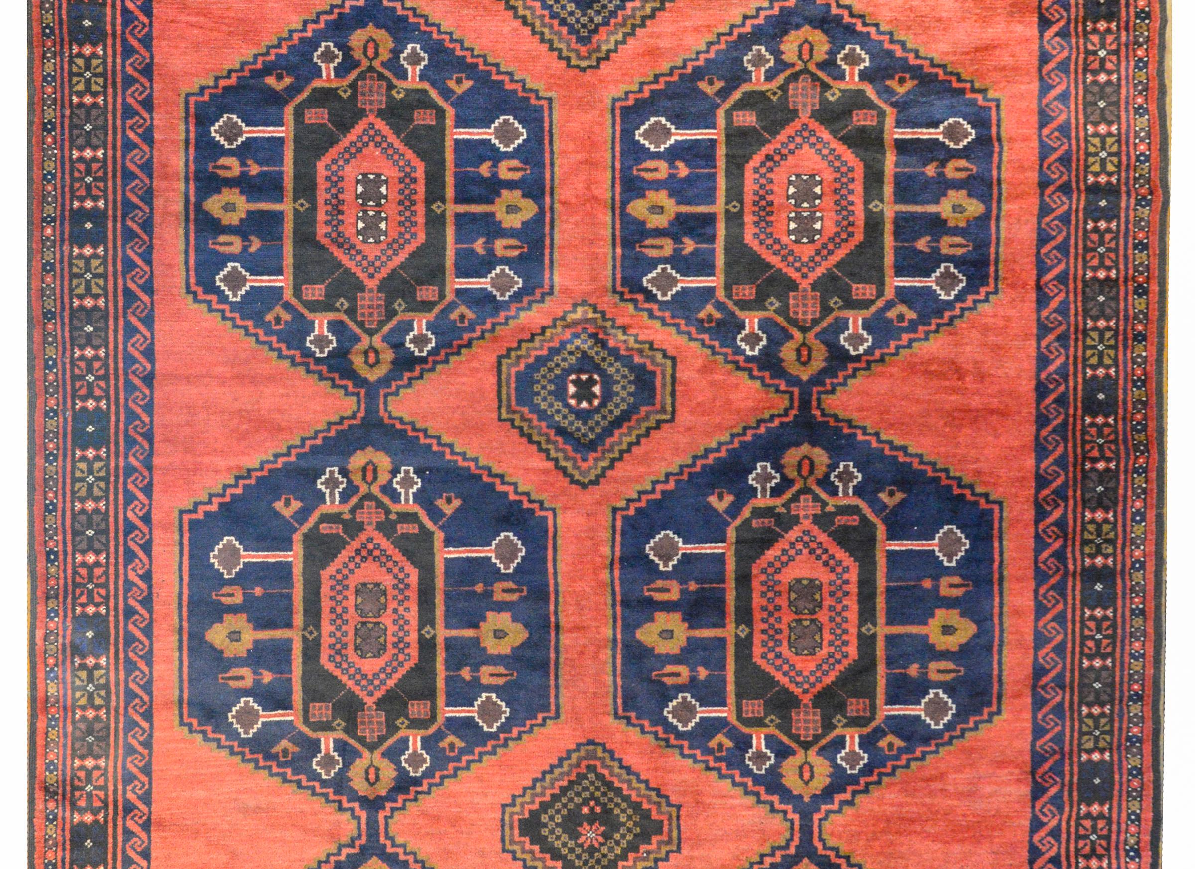 A fabulous vintage Afghani Ersari rug with eight floral and leaf patterned hexagonal medallions woven in crimson, white, brown, and black vegetable dyed wool, all with dark indigo backgrounds against a bold crimson background. The border is