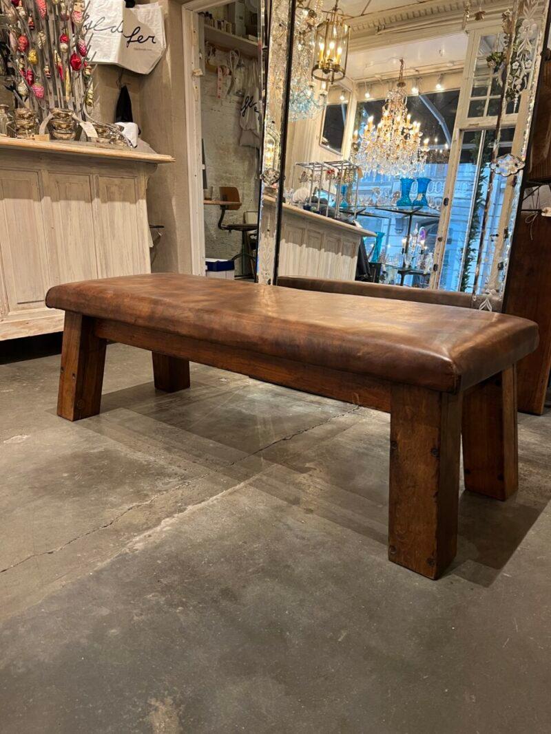 Super cool, large and old school vintage dark leather bench. Originally a plinth from an old gymnastic hall, and hand picked from France. Has a wooden base. 

Would be fabulous as bench to tie your shoes up in a hall, coffee table, gallery seating