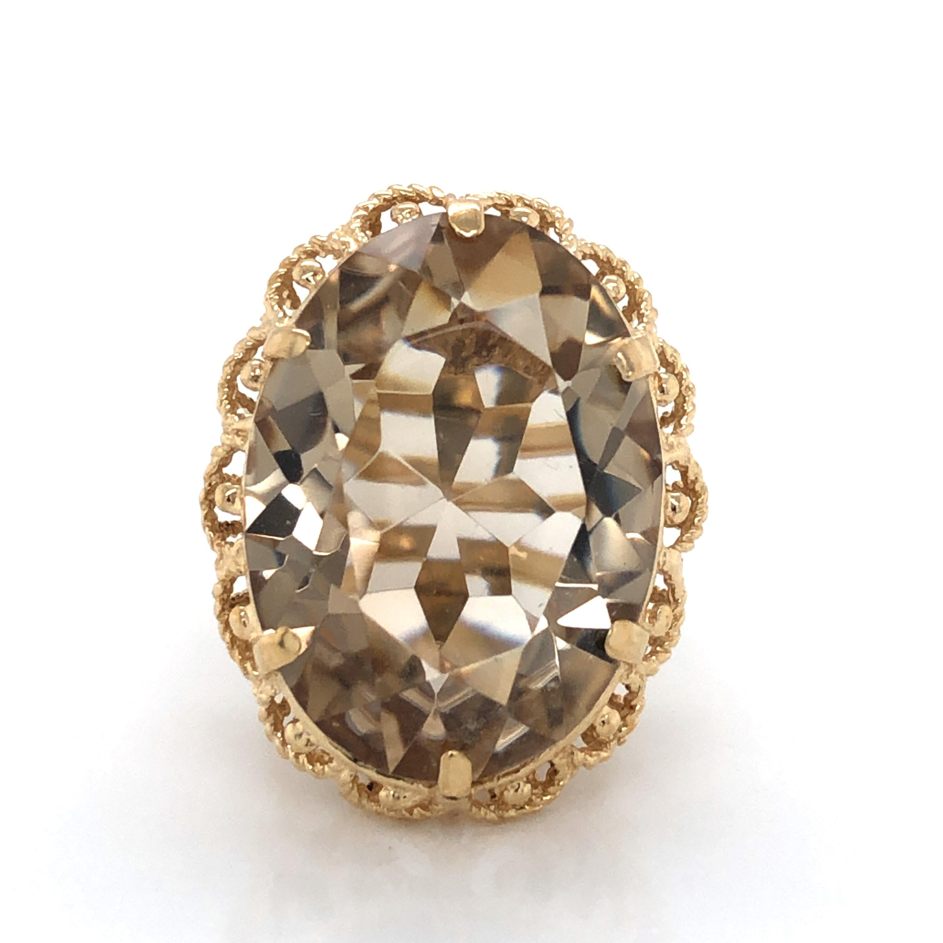 The twenty five carat oval center facet cut smoky quartz stone makes a bold statement as it glistens atop the finely crafted 11k yellow gold raised basket gallery setting. The warm sable color oval stone of this circa 1950's cocktail ring measures