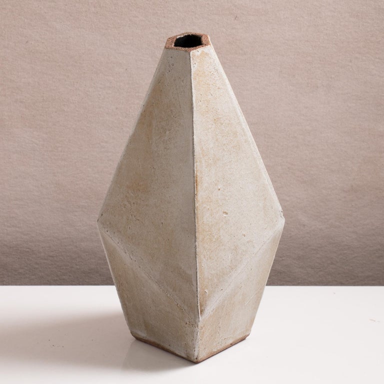 Inspired by midcentury brutalist architecture, this tapered ceramic vase combines clean geometric lines with the warmth and individuality inherent in handmade work. The complex geometric shape narrows to slender opening for flowers or small
