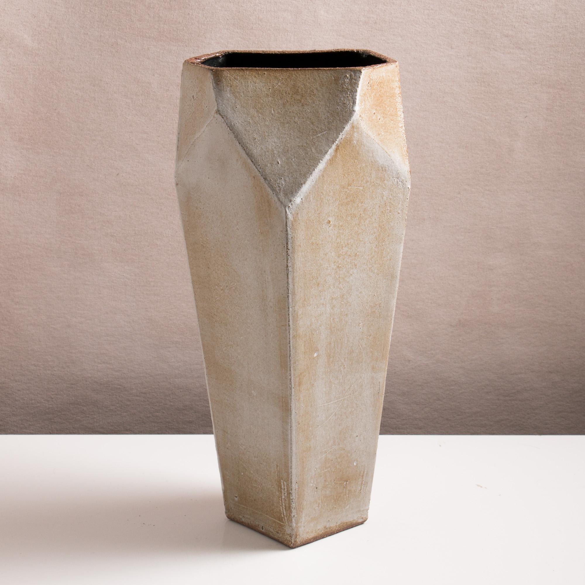 Inspired by midcentury Brutalist architecture, this tall ceramic vase combines clean geometric lines with the warmth and individuality inherent in handmade work. The shape is simple and elegant, with geometric facet detailing at the opening. Each