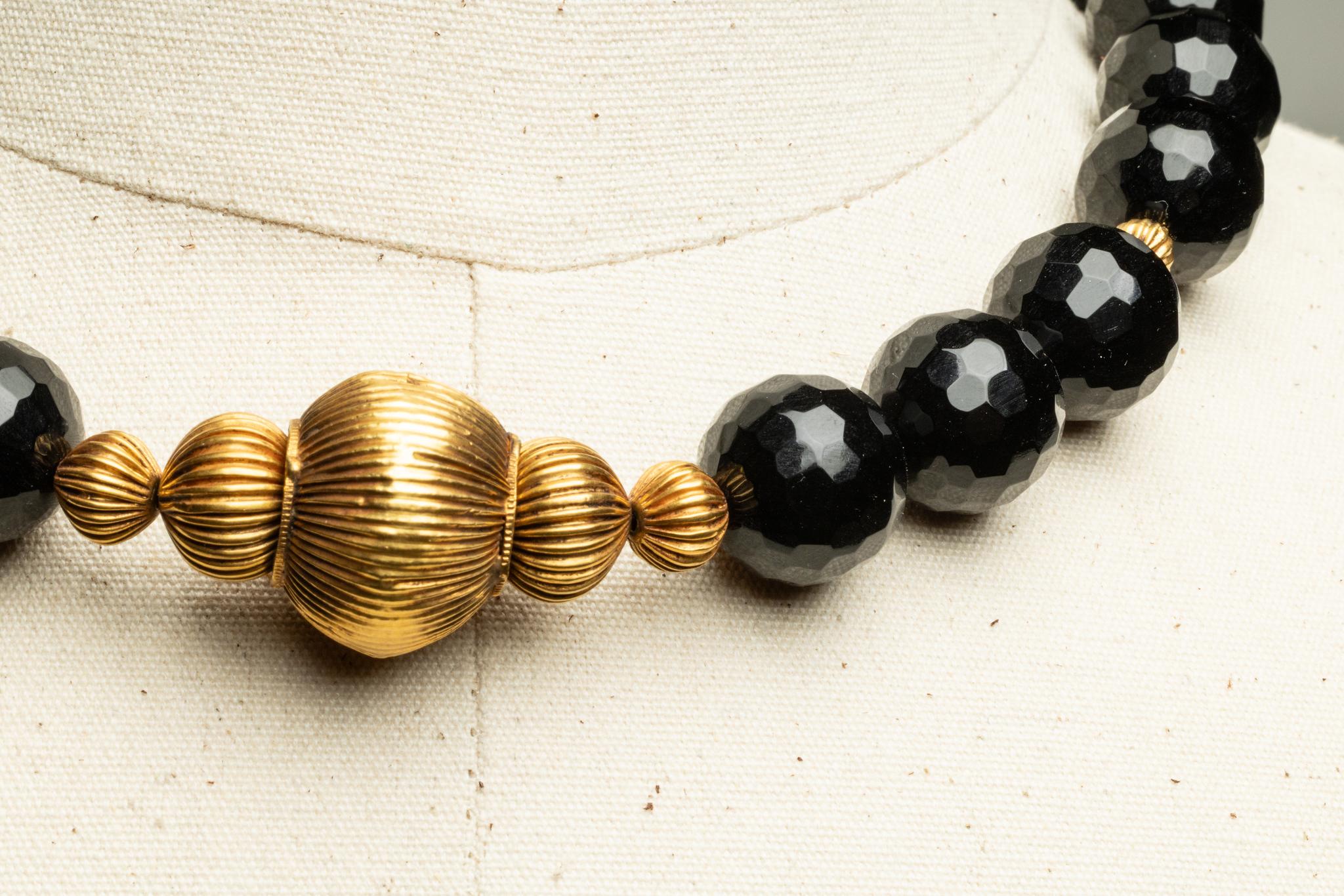 Un'incredibile collana di perle grandi e sfaccettate di onice nero con cinque perle graduate a forma di melone in oro 22K al centro.  Ha una catena d'oro sul retro con una chiusura a moschettone e la catena è regolabile per portare la collana da 18