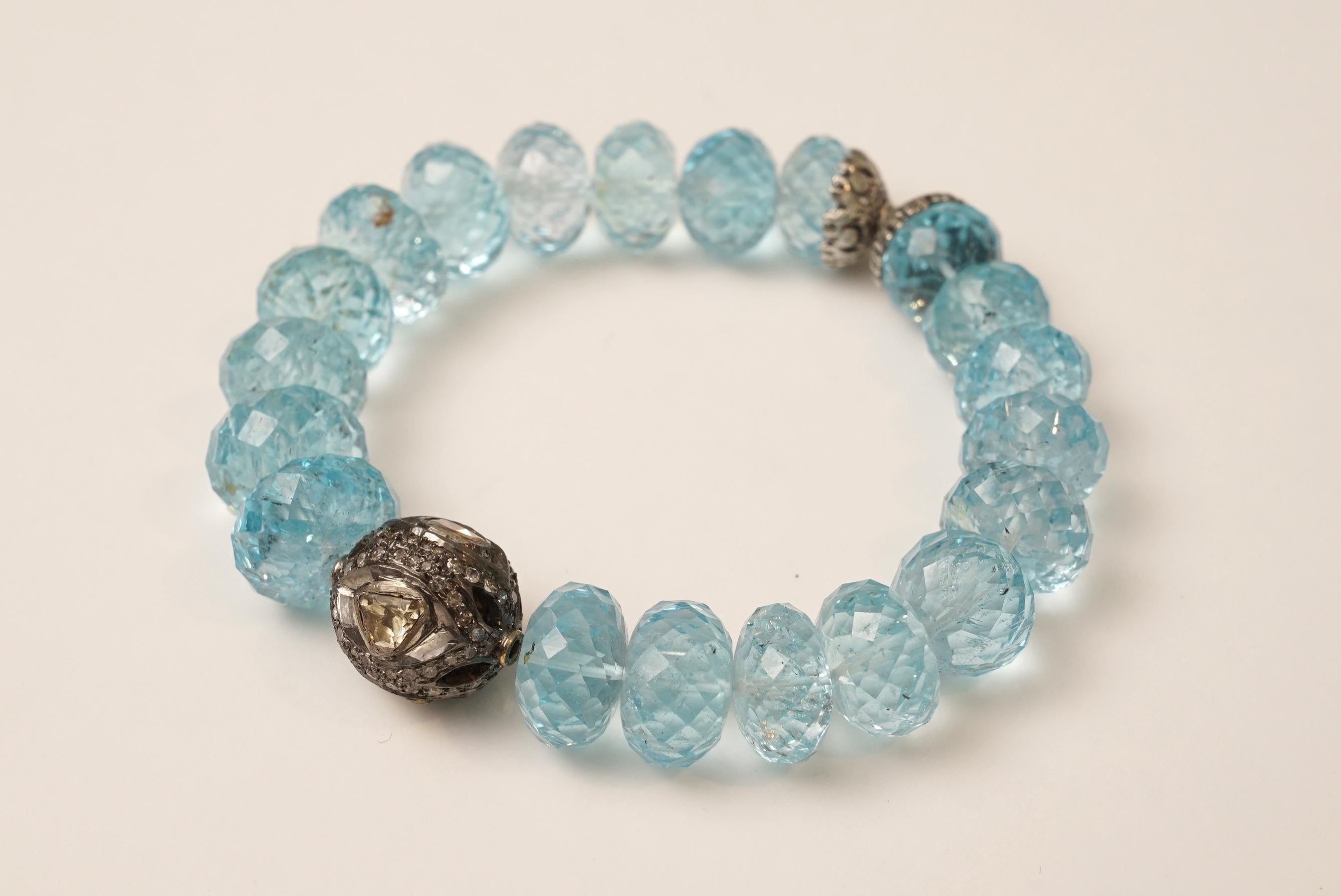 Lovely faceted blue topaz beaded bracelet with sterling silver with 4 rose cut diamonds surrounded by pave`-set diamonds on the center bead and two sterling silver end caps opposite.  Strung on a nylon stretch cord for easy on and off.   Great sized