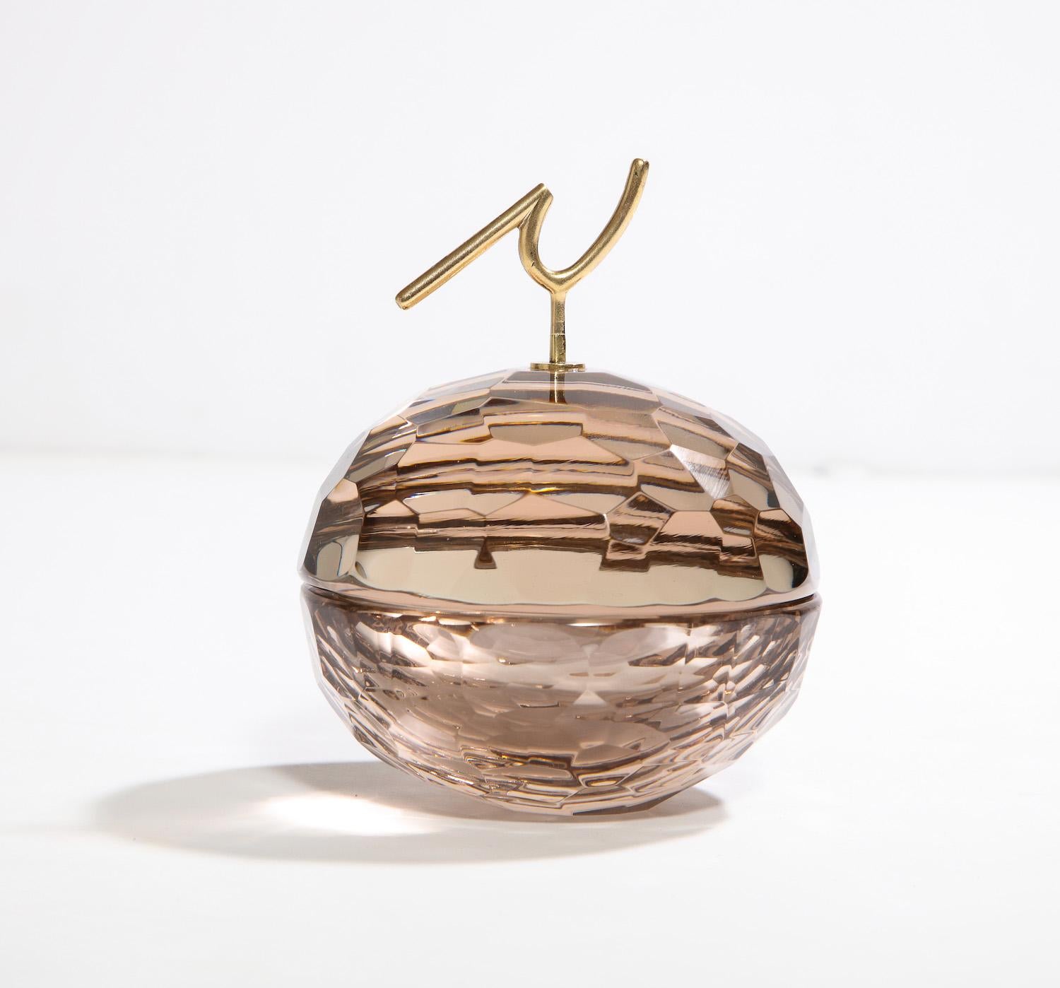 Covered Bowl by Ghiró Studio. Studio-made covered bowl of hand carved glass. Champagne-colored glass featuring faceted exterior and all polished edges. Cast-brass handle and artist signed underneath.