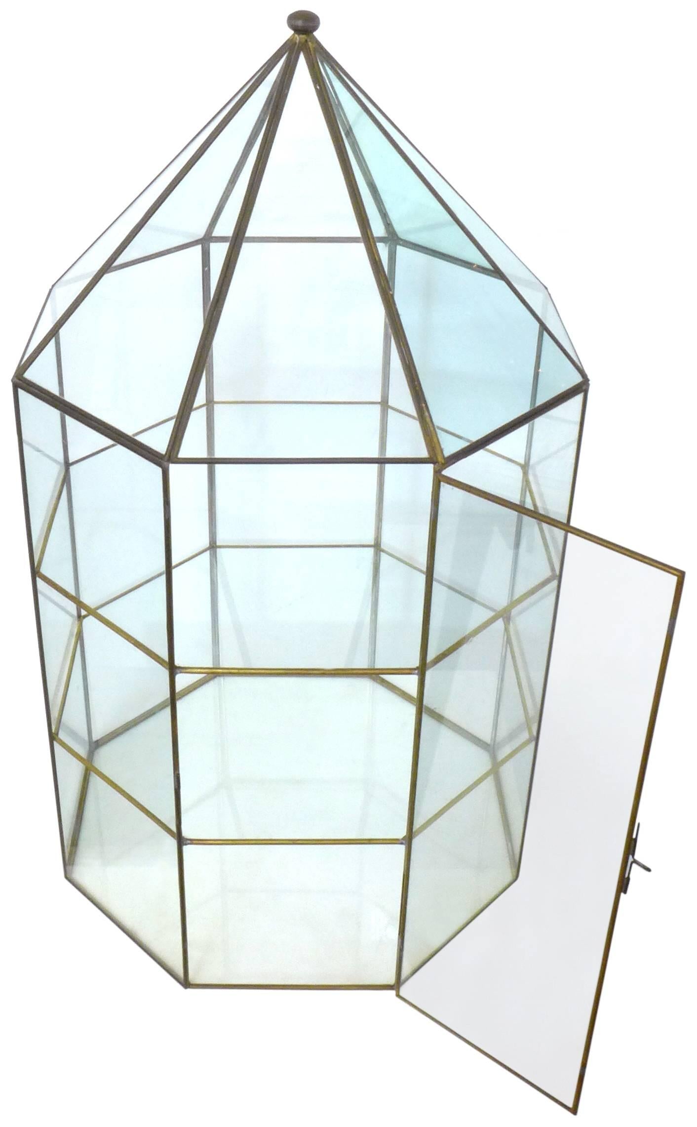 A beautifully crafted brass and glass vitrine. Delicate, perfectly-patinated brass frame-work holding each pane; an octagonally facetted-cylinder, pyramidally-tapering at the top to a small, spheroid finial. A nearly-indiscernible, single, latched