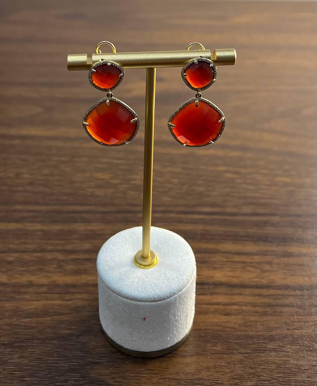 Un par de pendientes llamativos y elegantes.
Estos pendientes presentan vibrantes piedras de cornalina roja anaranjada, cada una engastada en una delicada montura de oro de 14k.
Las piedras están dispuestas en un diseño de doble gota, con una piedra