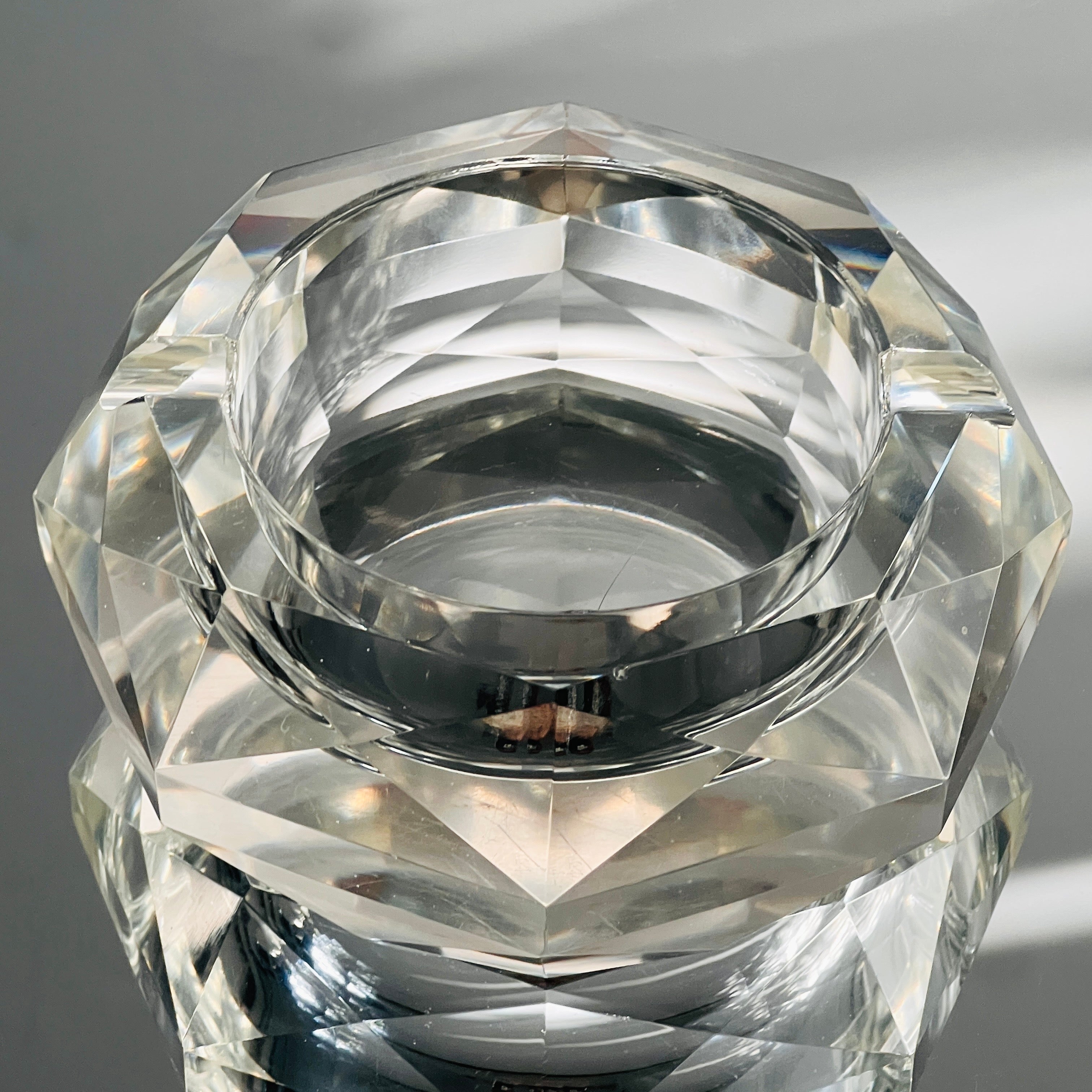 Mid-Century Modern cut crystal ashtray with faceted design. The ashtray is predominantly round in form but has eight sides creating prisms of light. Heavy in weight and fitted with two cigarette notches. Can be used as decorative object. Makes a