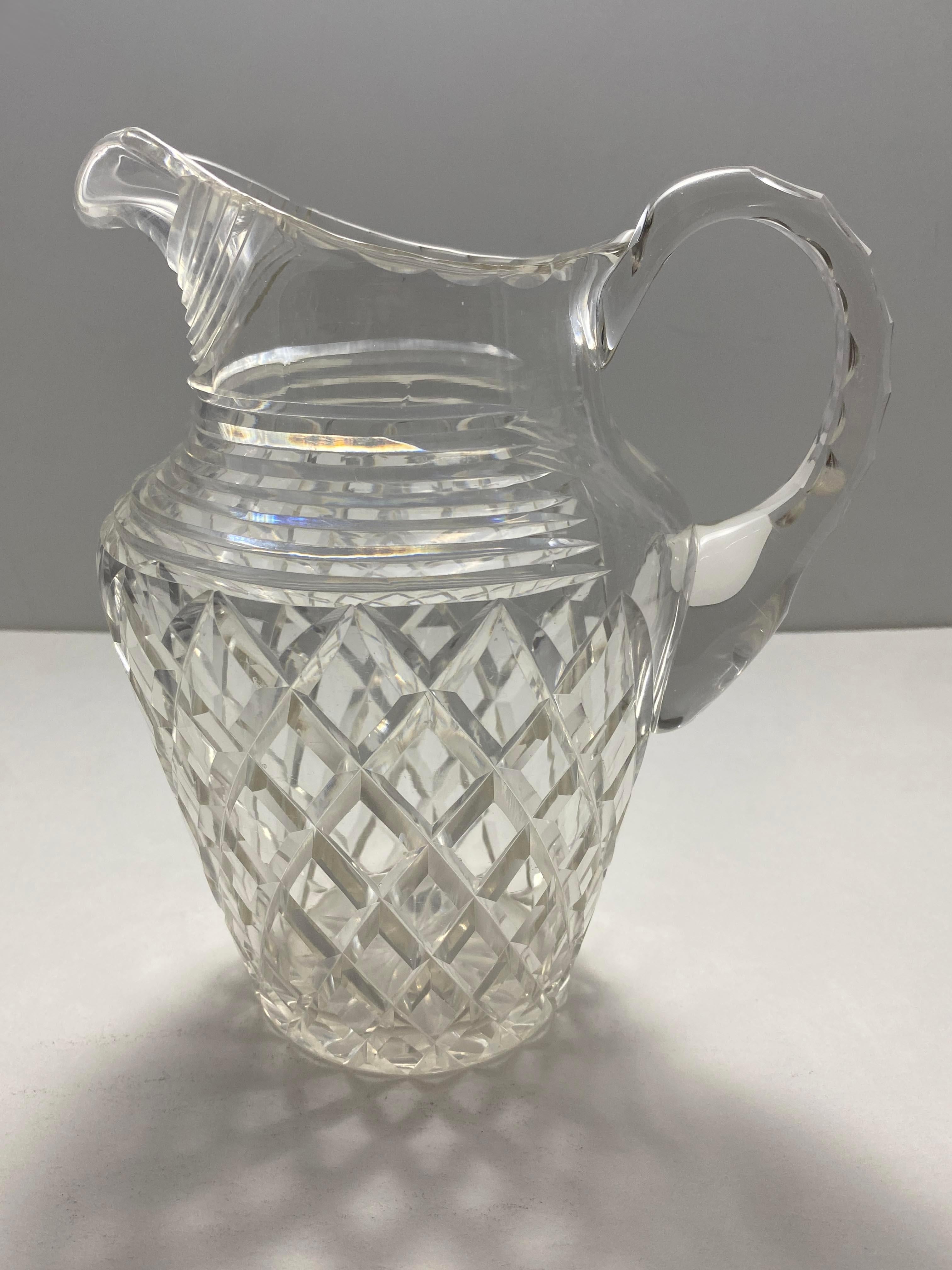 A dazzling crystal faceted pitcher, an exquisite addition to elevate your table setting with a touch of glamour. Though unsigned, this pitcher exudes a timeless elegance, showcasing its craftsmanship through brilliant facets that catch and reflect