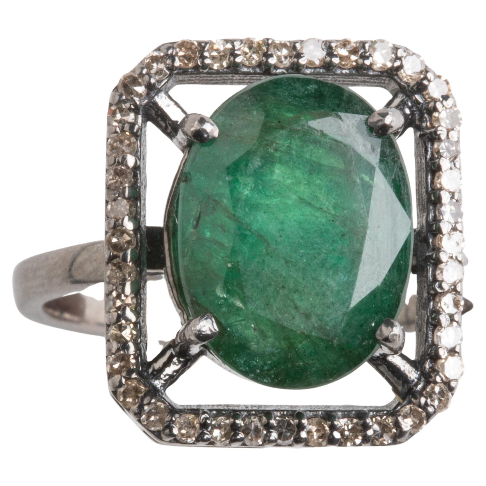 A large, oval faceted Zambian emerald with a rectangular shaped border of diamonds in a pave` setting.  The diamonds total .27 carats, the emerald is 5.70 carats.  Ring size is an 8.