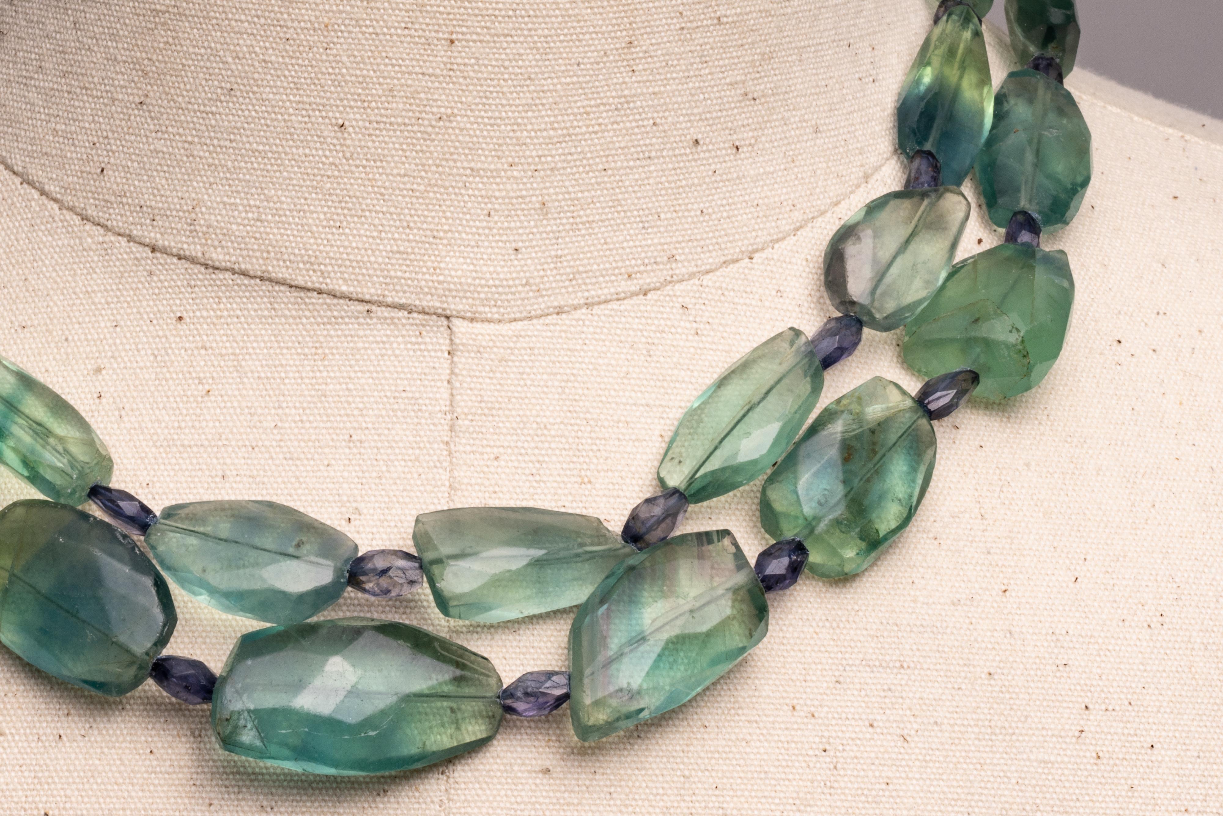 A beaded, double strand of tumbled, faceted fluorite gemstones with faceted oval iolite gemstones in between.  A rainbow moonstone clasp in sterling silver.  By Deborah Lockhart Phillips