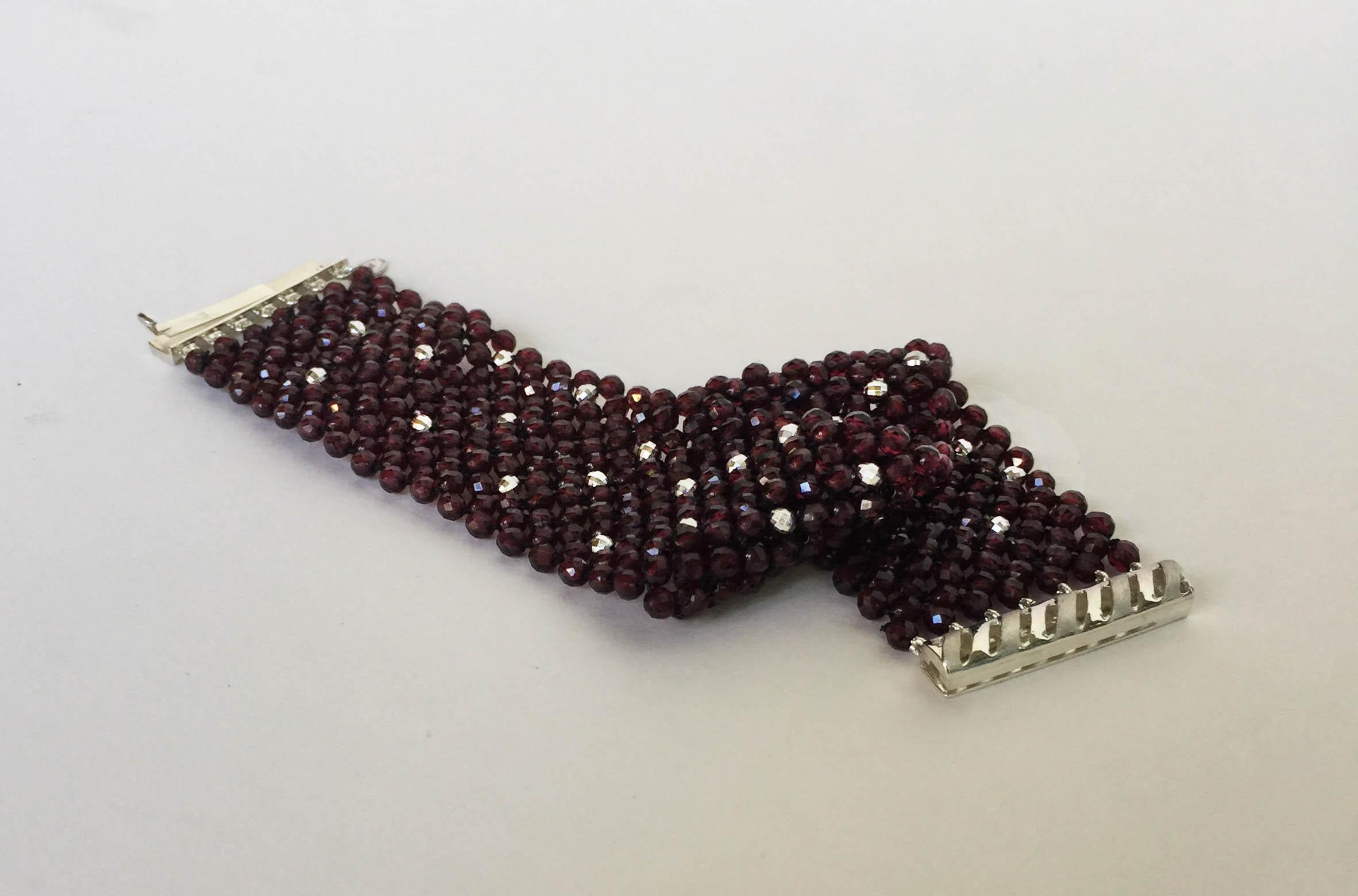 This bracelet features intricate woven Garnet beads that display a remarkable shine accented by high shine sterling silver facets. This bracelet meets at a secure sterling silver sliding clasp that locks. Measuring at 7.3 inches long and is 1.1