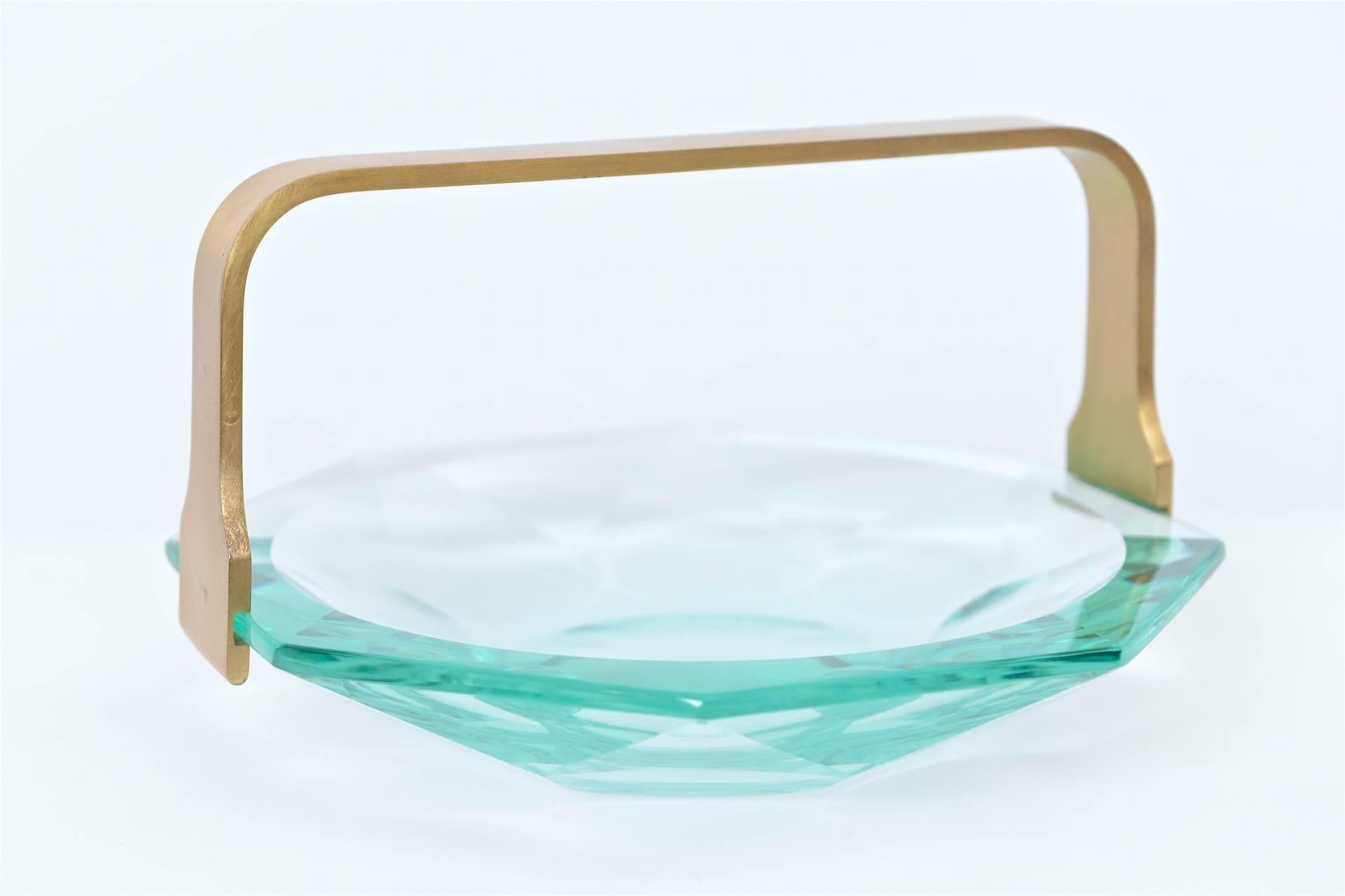 This exquisite aquamarine glass centrepiece dish was designed by Max Ingrand for Fontana Arte in the 1960s. This design features a simple brass handle for carrying whilst the many facets in the glass capture and reflect the light beautifully. A