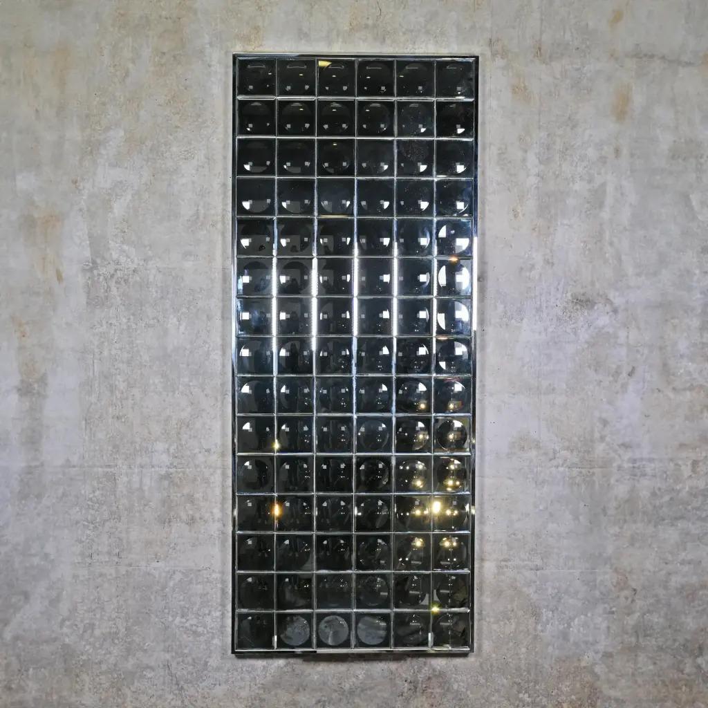 Ce miroir mural à facettes est une pièce décorative contemporaine inspirée des années 1970. En verre miroir, elle est composée de petits miroirs carrés qui créent un effet visuel kaléidoscopique, à la fois lumineux et graphique.
Chaque facette
