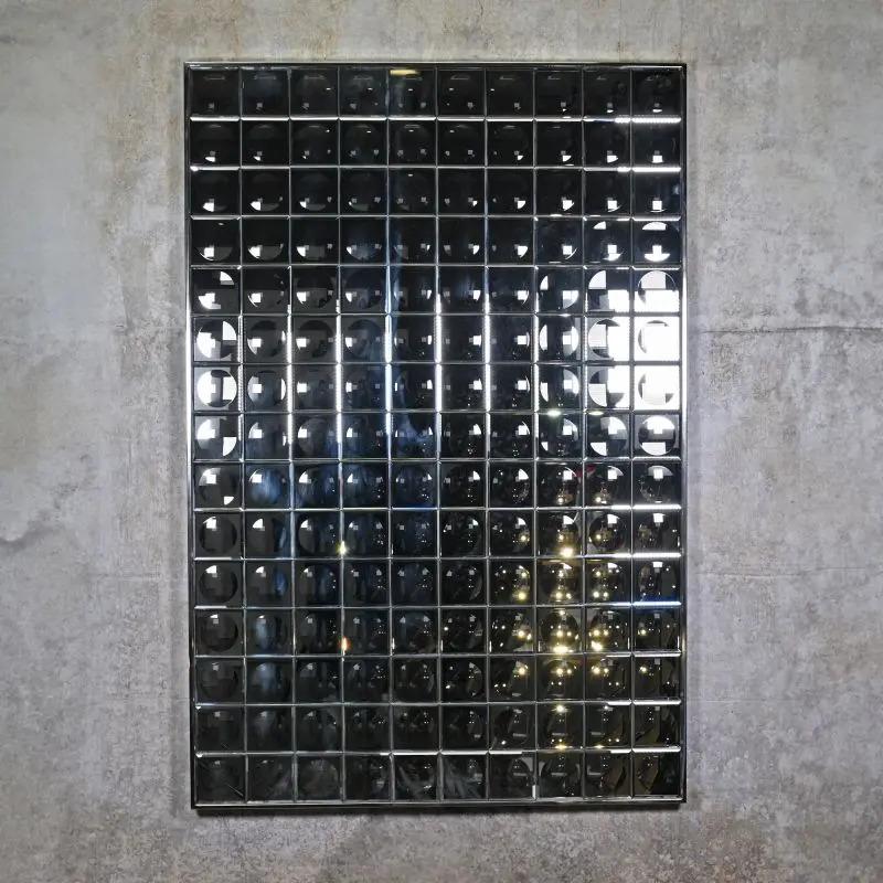 Ce miroir mural à facettes, de taille L, réinterprète de manière contemporaine le design futuriste des années 1970. Composé de multiples petits miroirs en verre, il crée un effet kaléidoscopique sur le mur. Chaque facette réfléchit la lumière