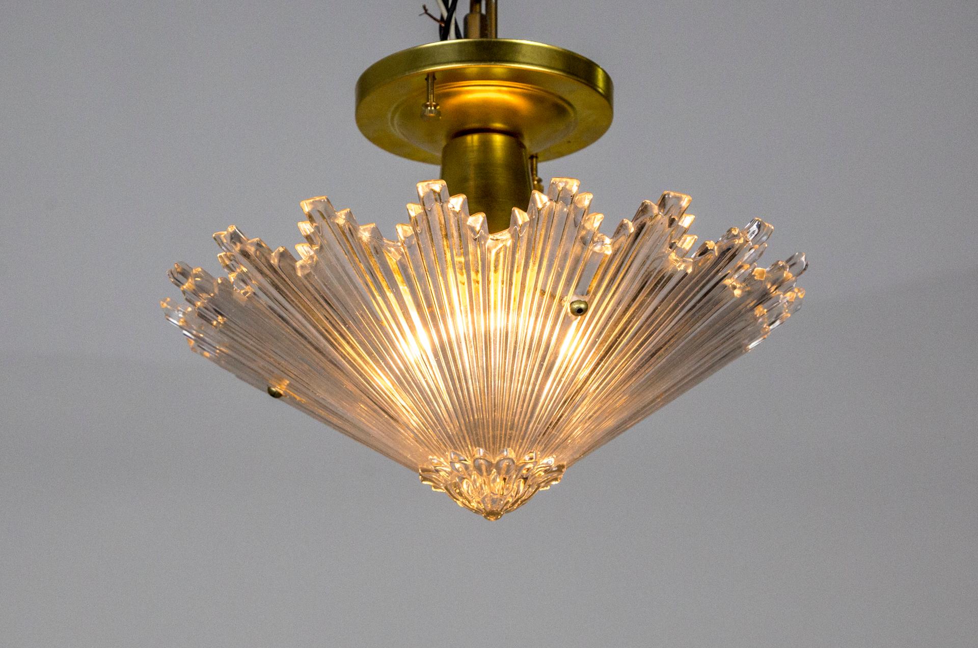 A light fixture made with a complex, molded glass star in a downward cone shape. It is held with a brass mount, newly made with antique, Art Deco glass. 1930s, France. 9