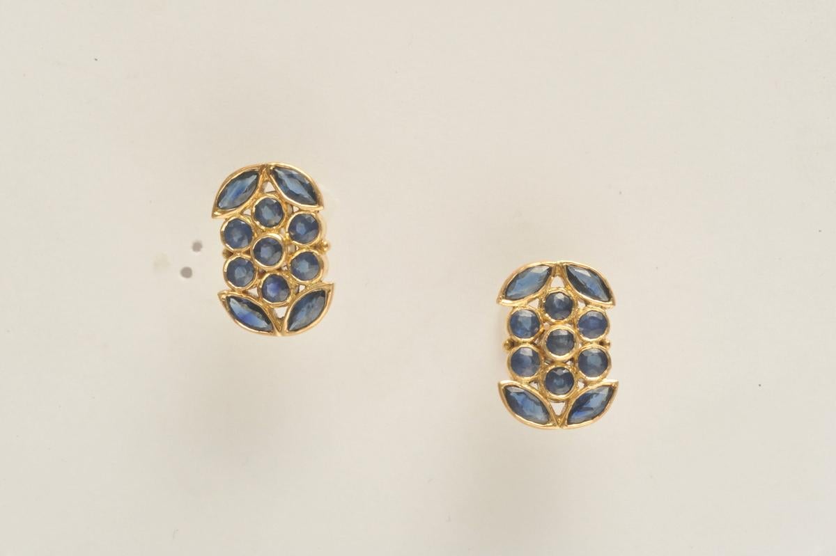 A lovely faceted mosaic of round and marquise cut blue sapphires bordered in 18K gold.  Gold post for pierced ears.  If you look closely, the flower in the center is flanked by marquise cut sapphires as the leaves.