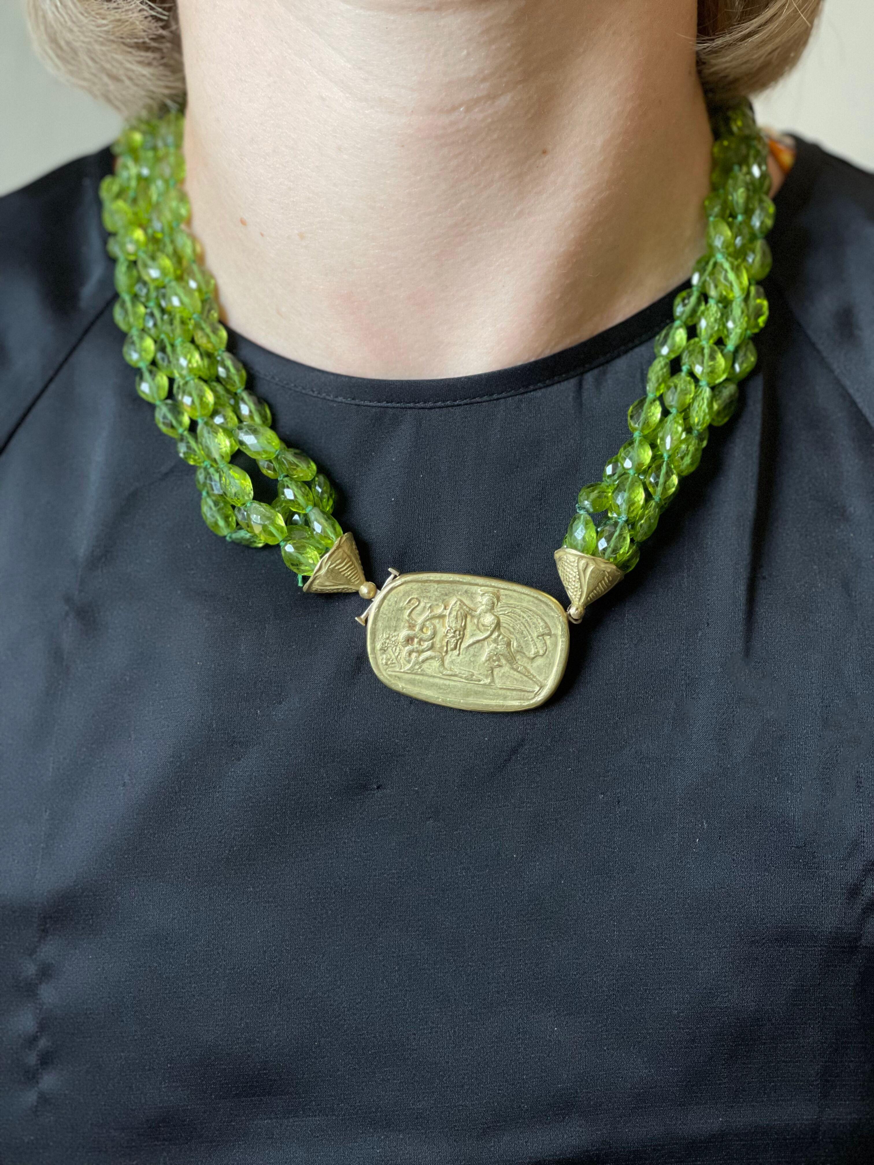 18k gold necklace with 5 strands of faceted peridot gemstones. The center pendant depicts  roman soldier. Necklace is 21
