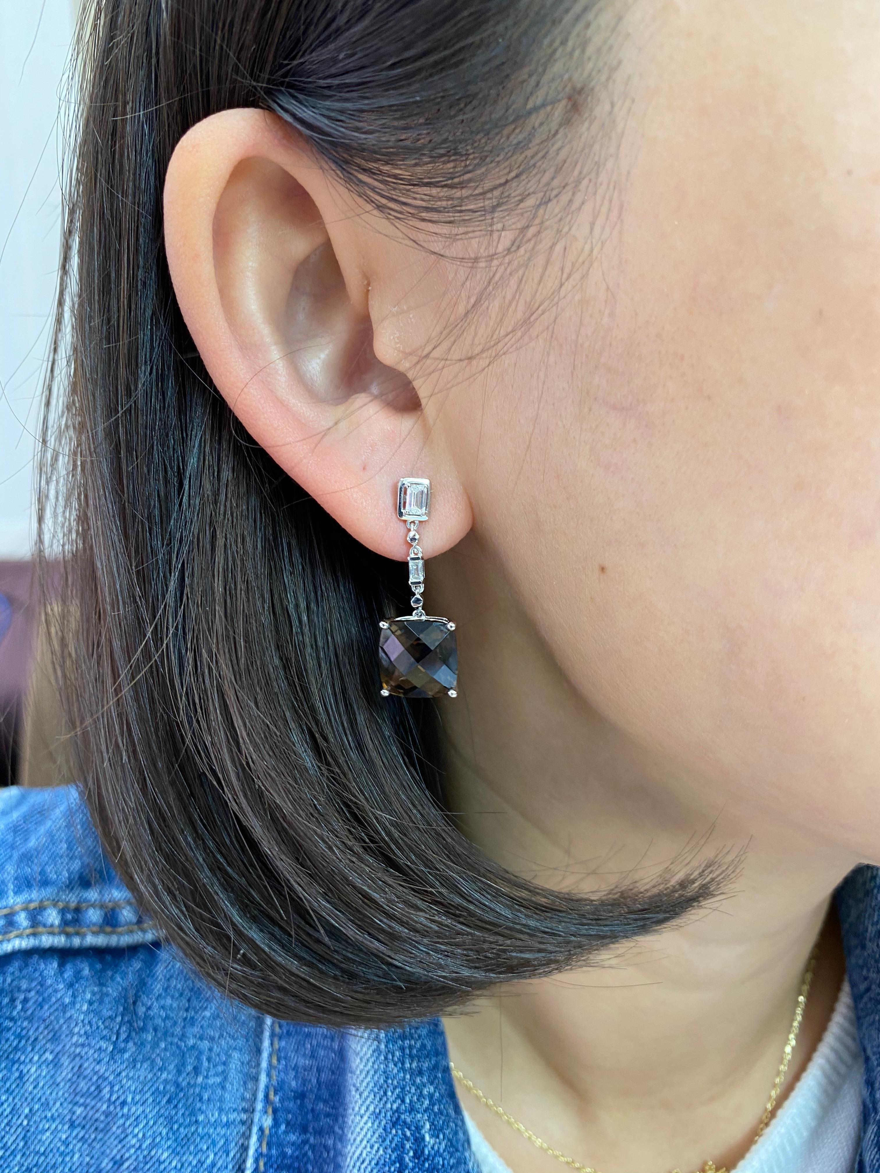 Here is a fantastic pair of drop earrings. The earrings are set in 18k white gold. The two nicely faceted smoky quartz are 10 cts in total weight. There are 4 emerald step cut diamonds totaling 0.49cts that make up this pair of drop earrings. The